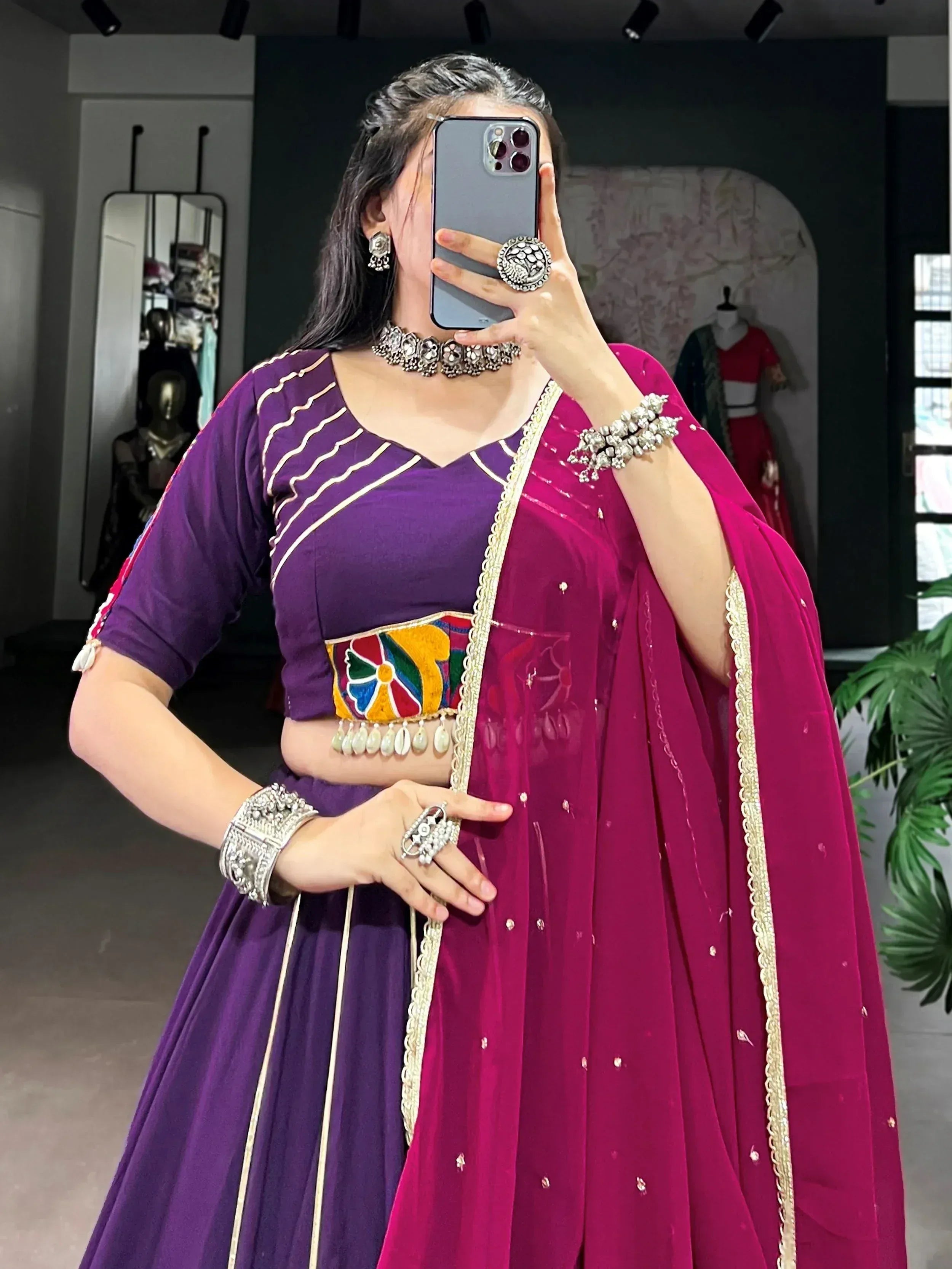 Purple lehenga choli with colorful embroidery and pink dupatta, styled with traditional silver jewelry