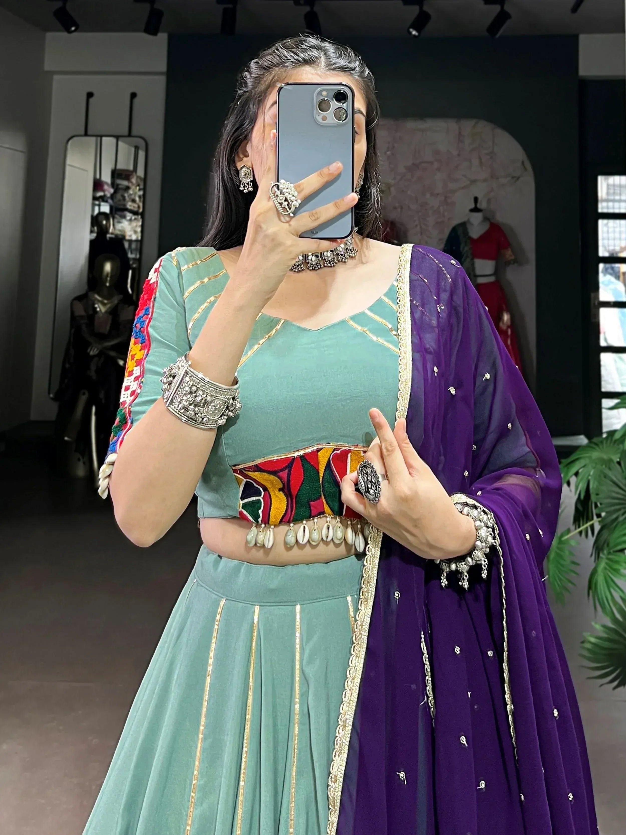 Woman in mint green lehenga choli with purple dupatta, colorful embroidery, and traditional jewelry