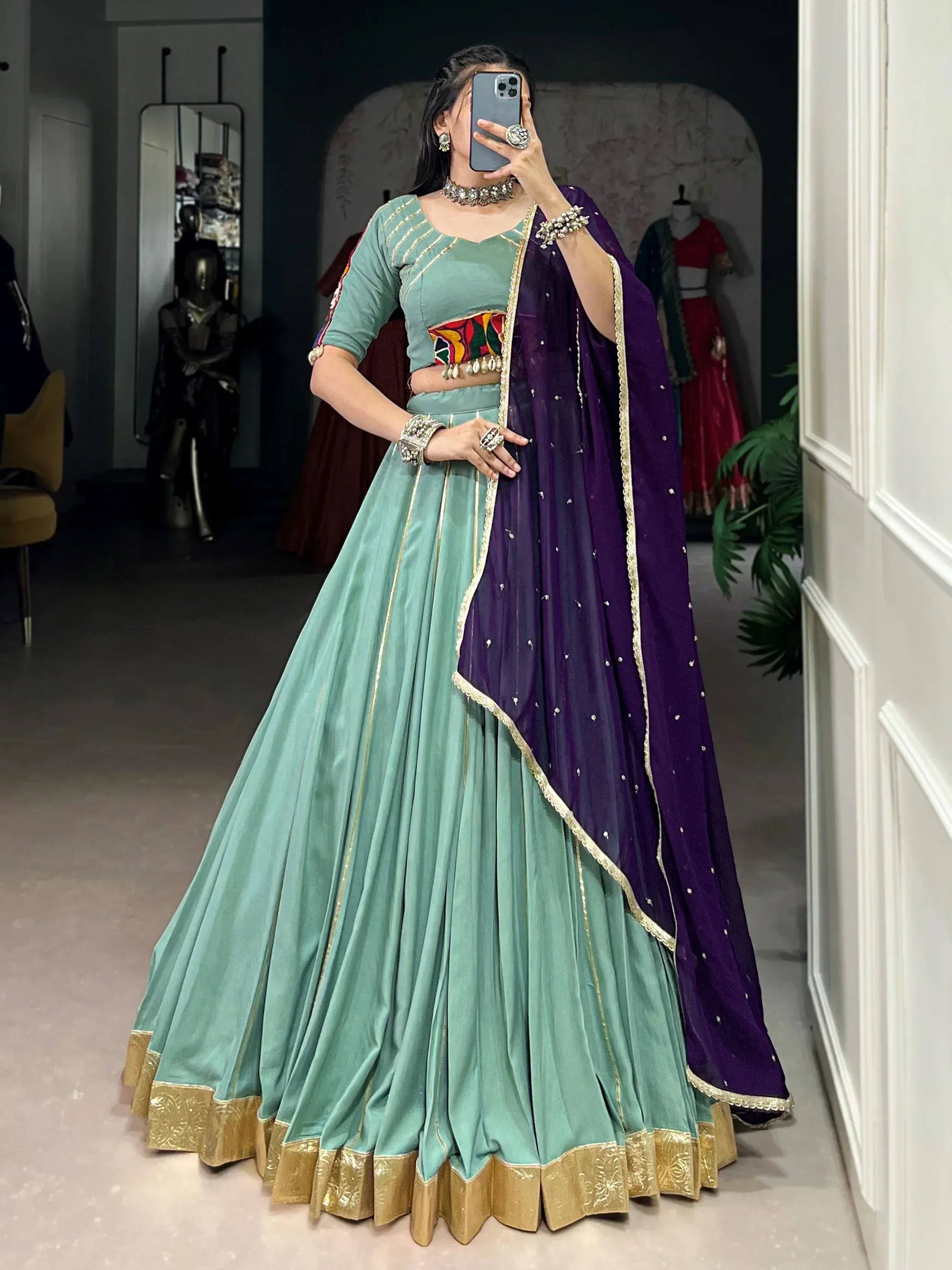 Mint green lehenga choli with purple dupatta, gold trim, and colorful embroidery for Indian ethnic wear.