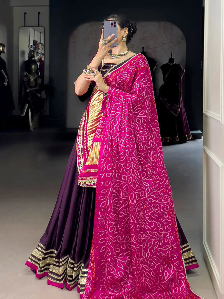 Woman in vibrant pink and purple designer lehenga choli with intricate embroidery, perfect for Indian ethnic wear.