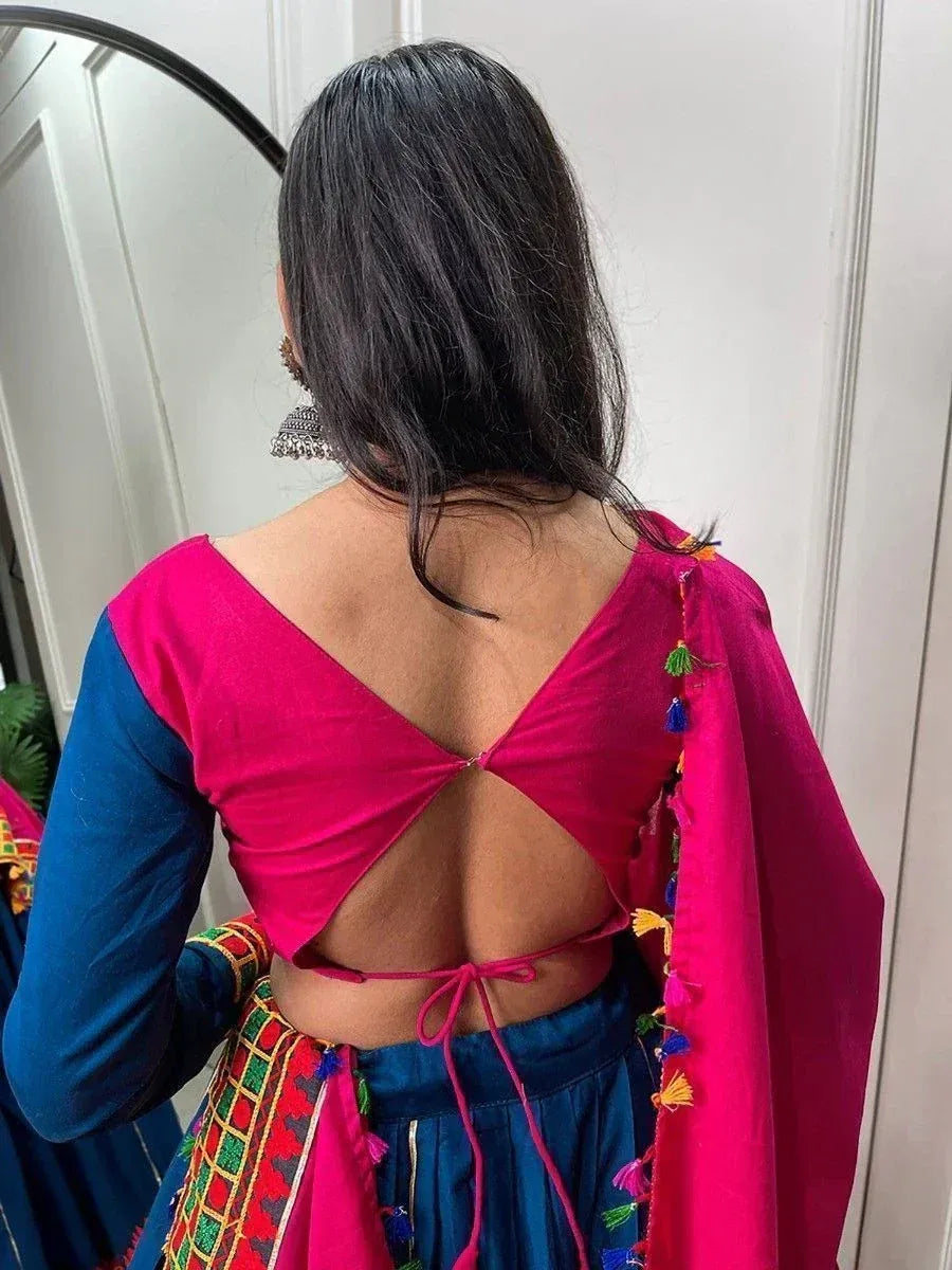 Back view of vibrant pink and blue ethnic lehenga choli with open back and tassel details