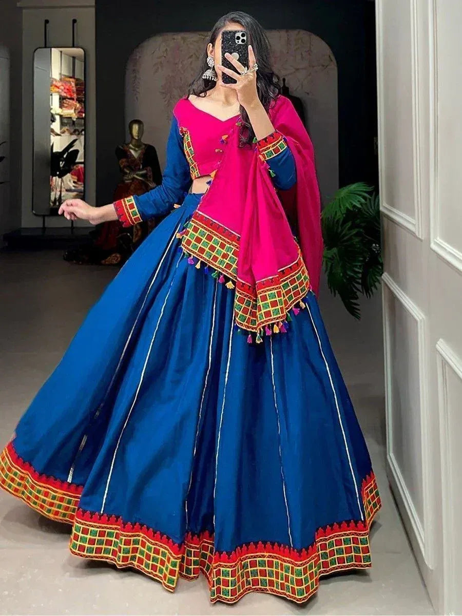 Blue and pink ethnic lehenga choli with mirror work and tassels, perfect for Indian weddings or festive occasions.
