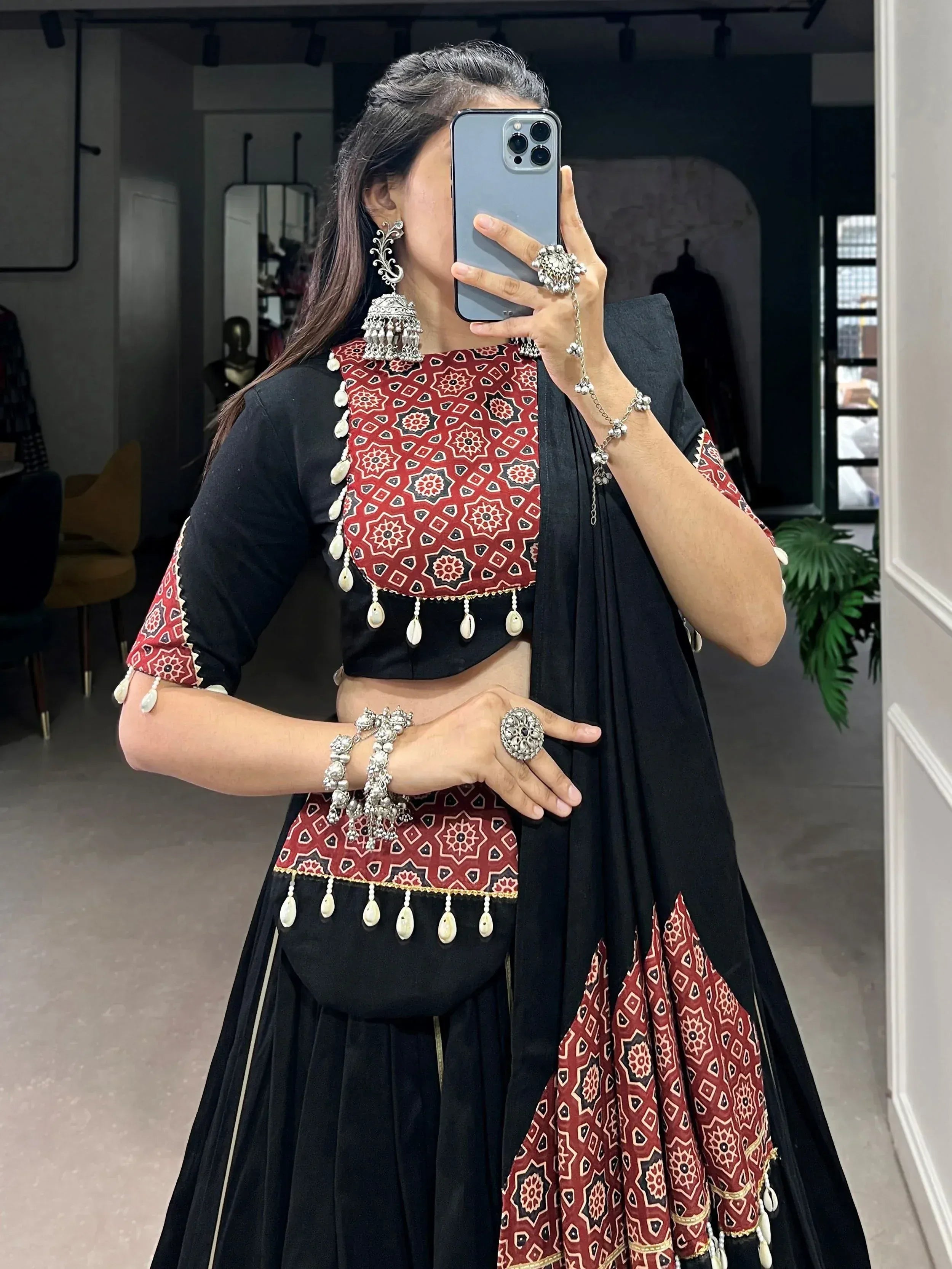 Black and red ethnic lehenga choli with mirror work, shell tassels, and traditional jewelry for Indian wear