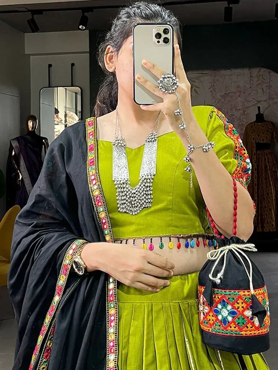 Vibrant green ethnic lehenga choli with black dupatta, colorful embroidery, and traditional jewelry