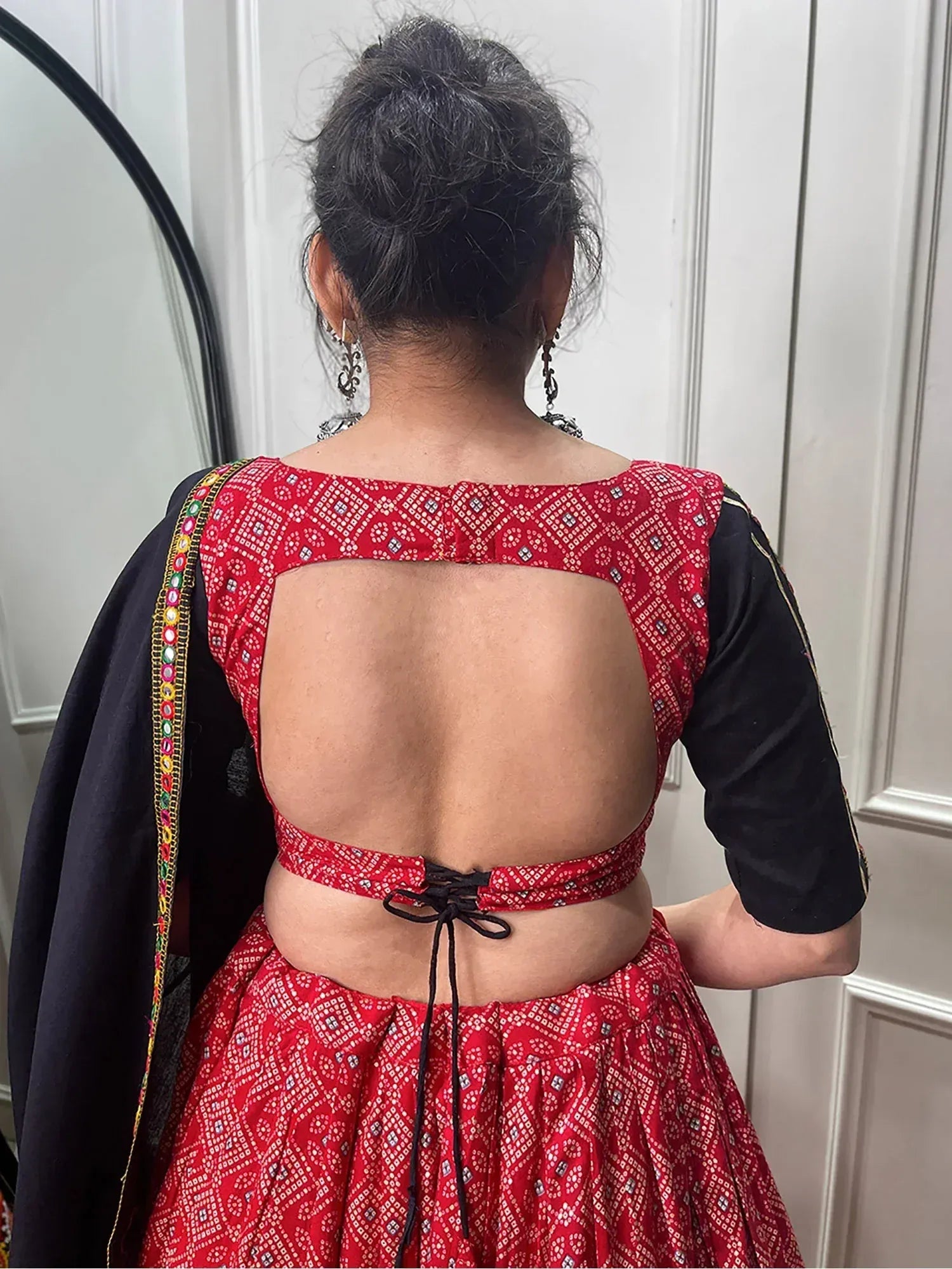 Red and black ethnic lehenga choli with backless design and mirror work, perfect for Indian festive occasions