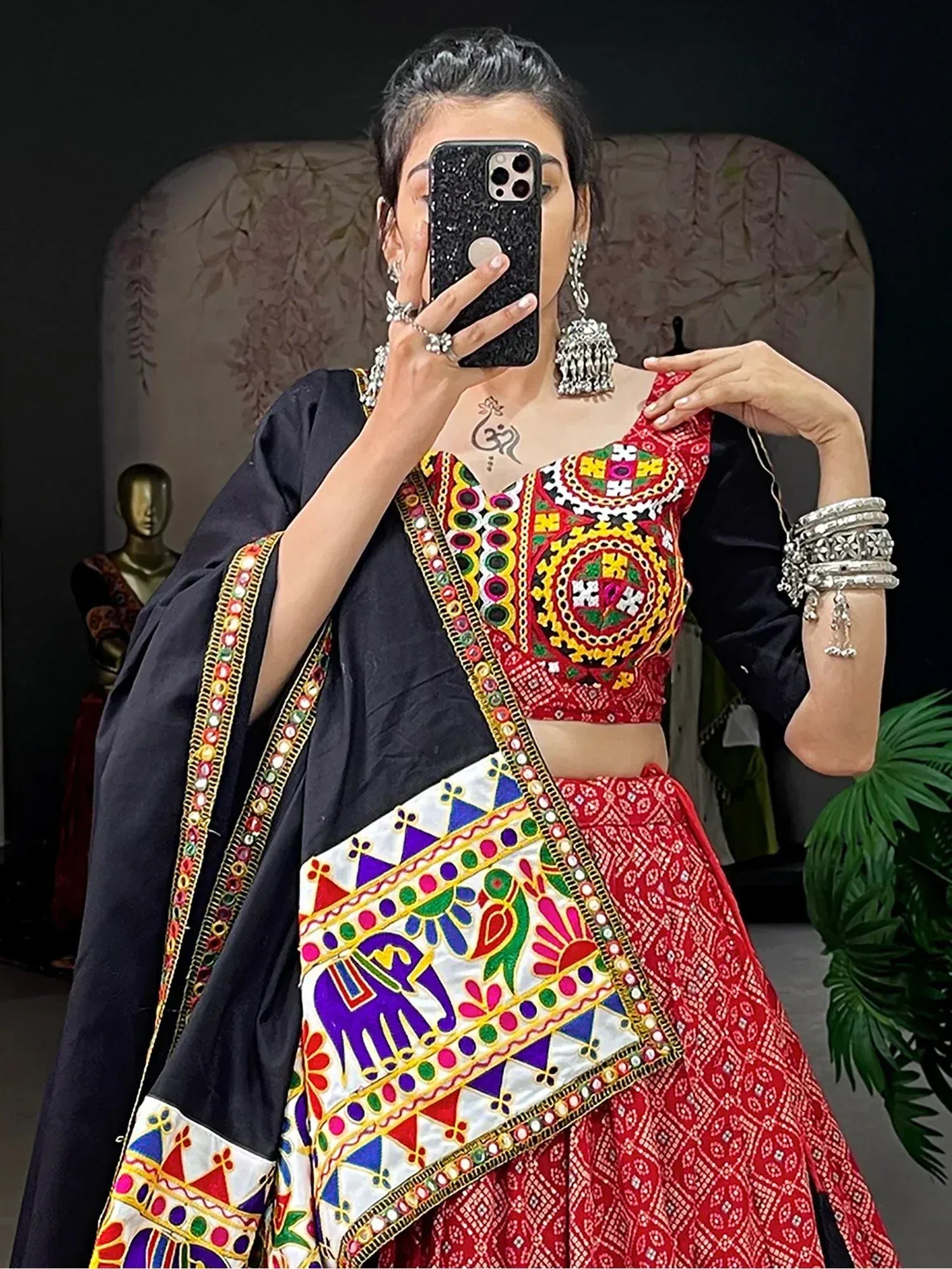 Vibrant red embroidered lehenga choli with mirror work, paired with black dupatta and silver jewelry for ethnic wear.