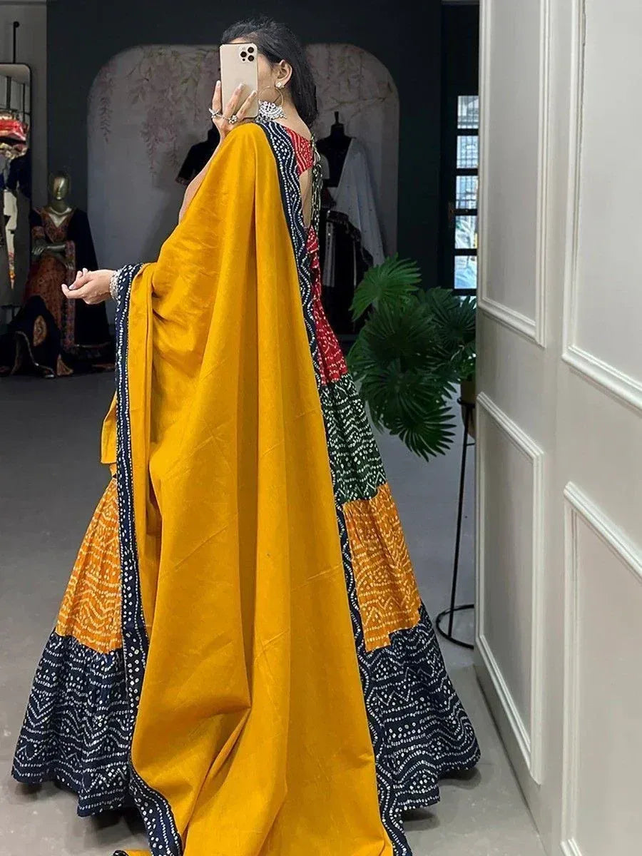 Woman in vibrant yellow and navy block print lehenga choli with mirror work, taking mirror selfie in boutique