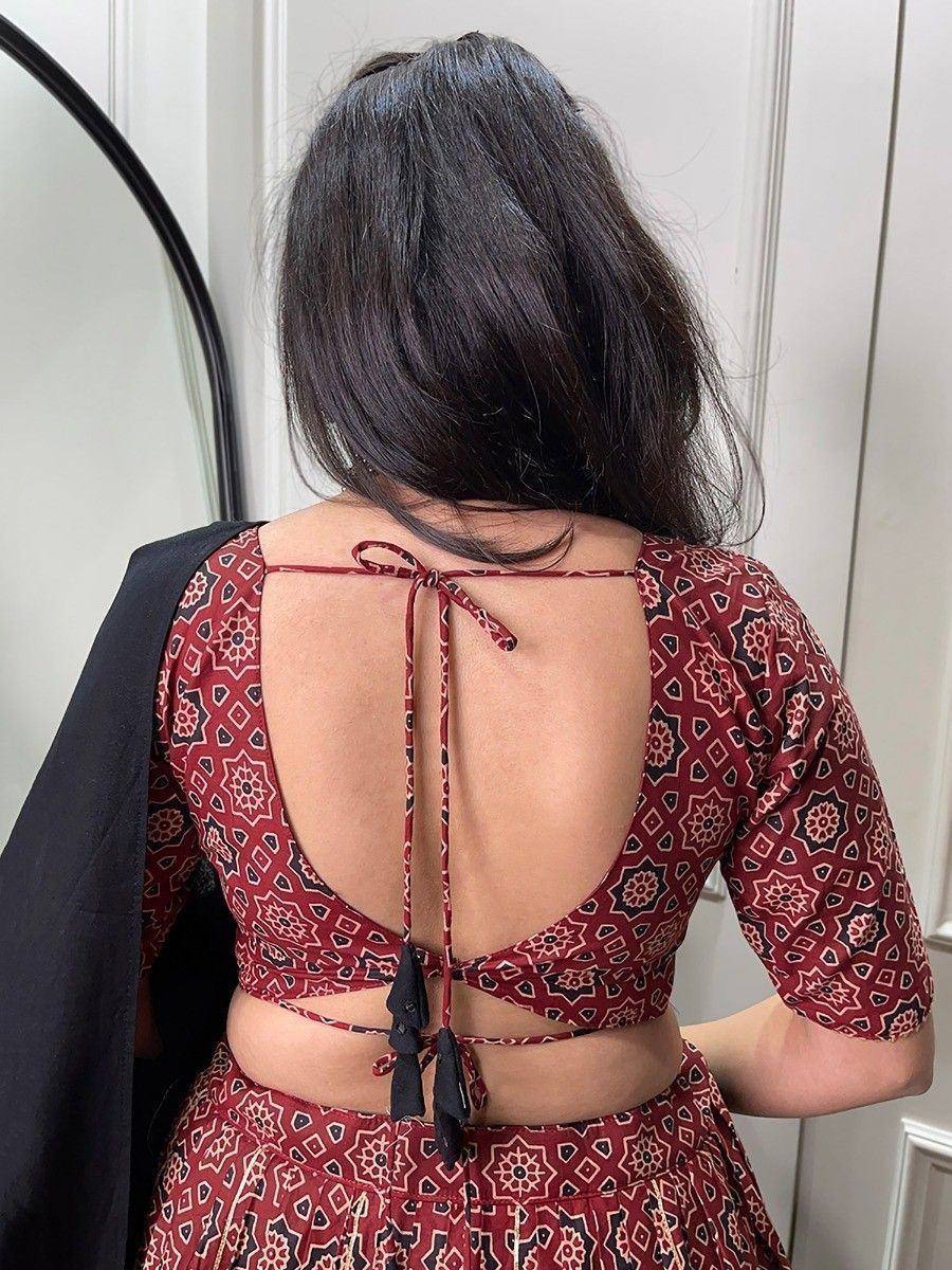 Back view of woman in maroon printed ethnic blouse with open back and tie-up detail