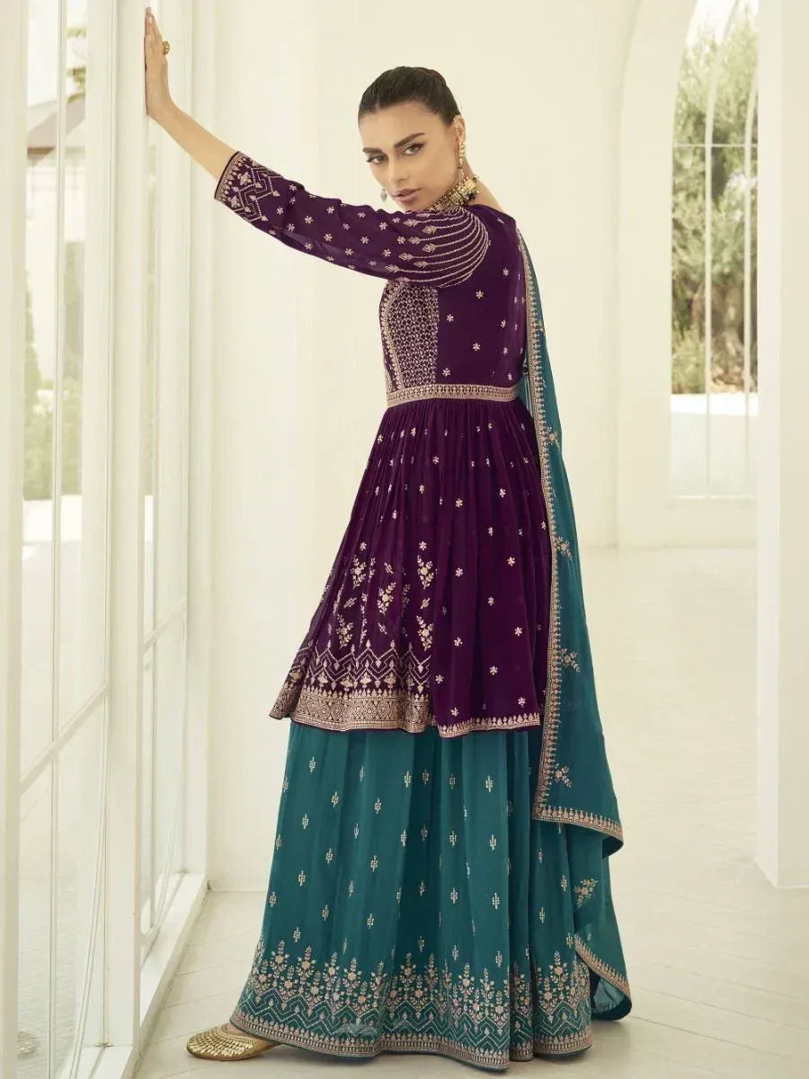 Woman wearing a designer purple and teal lehenga choli with traditional embroidery