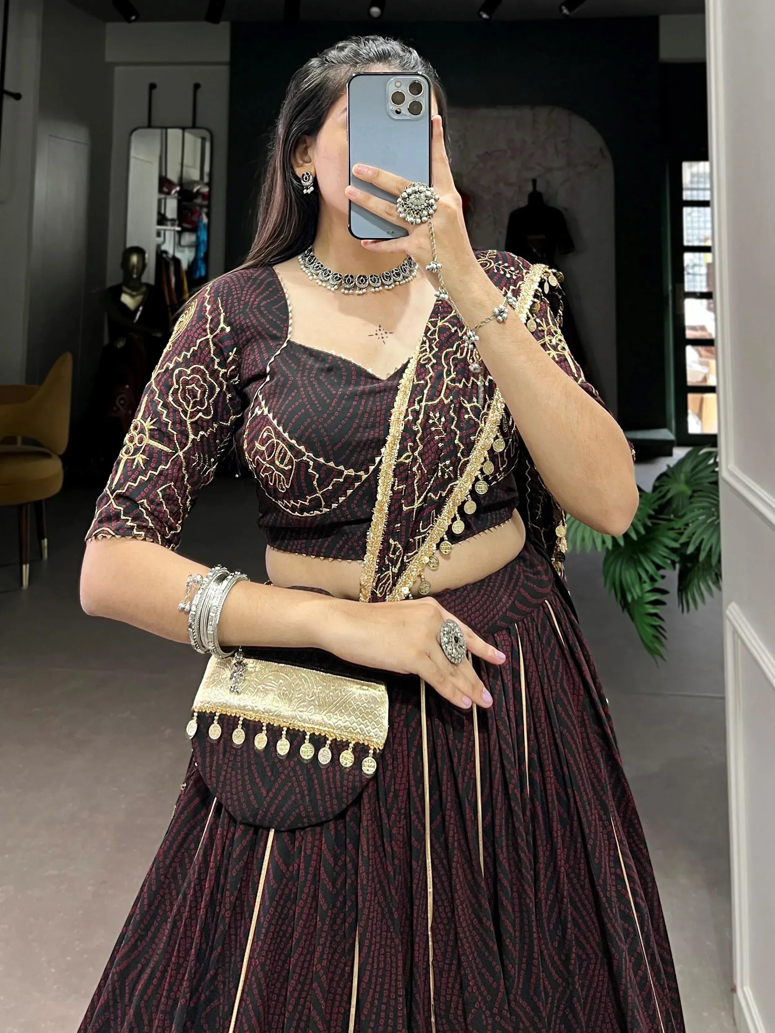 Woman in maroon and black embroidered lehenga choli with gold detailing and traditional jewelry