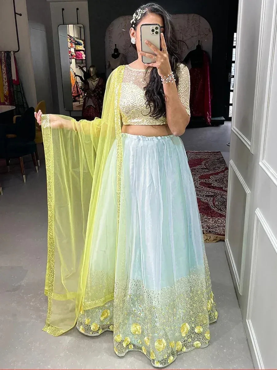 Woman in pastel blue and yellow lehenga choli with floral embroidery, perfect for Indian ethnic wear events