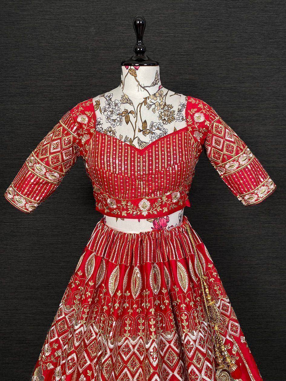Red embroidered lehenga choli with gold detailing, floral motifs, and geometric patterns on mannequin