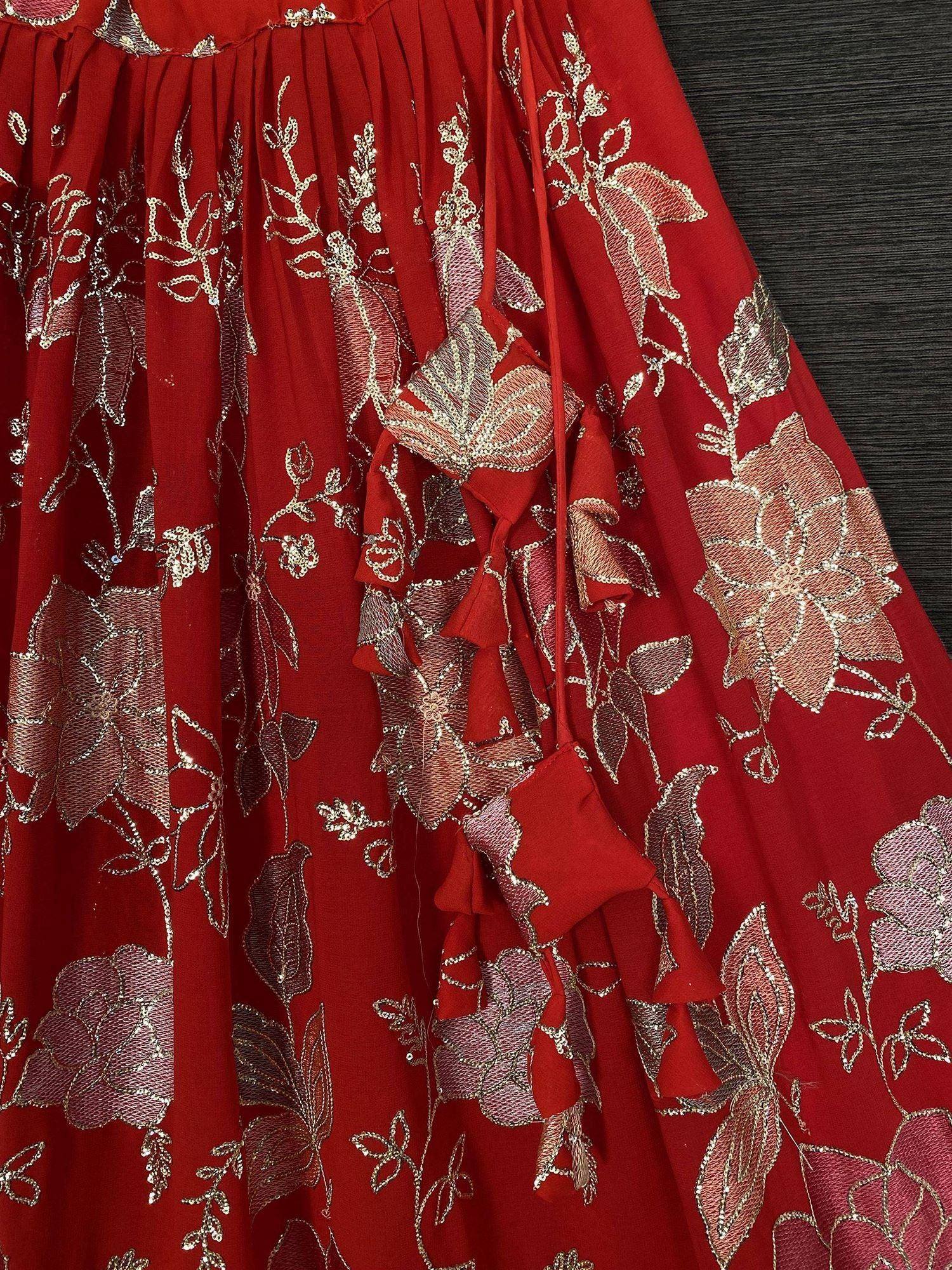 Red ethnic gown with gold floral embroidery and ruffle details, perfect for Indian occasions.