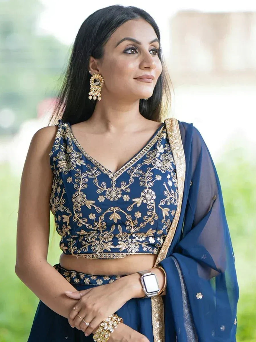 Woman in navy blue embroidered lehenga choli with gold floral detailing and matching dupatta
