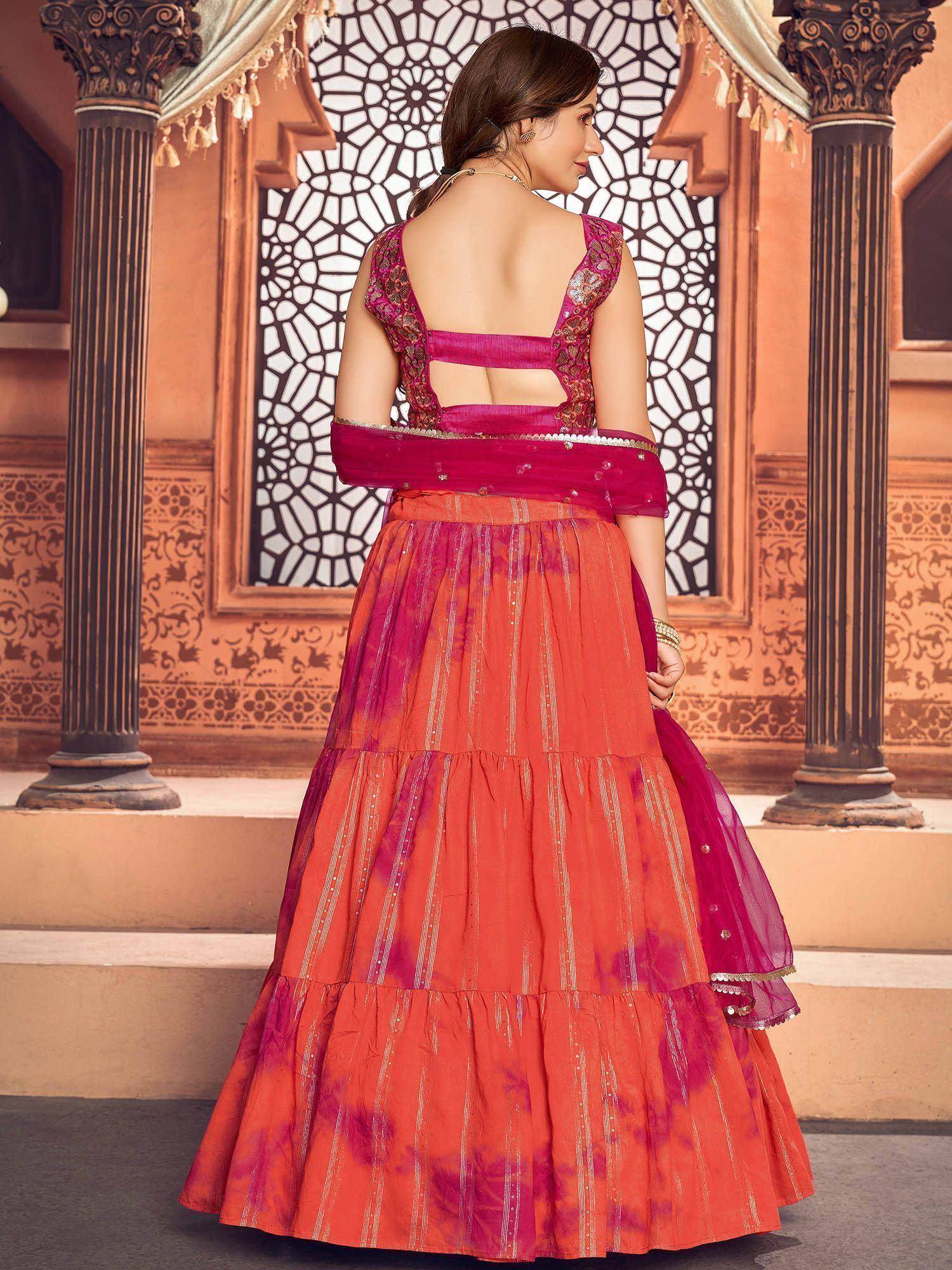 Woman in vibrant orange and pink lehenga choli with backless blouse, traditional Indian ethnic wear