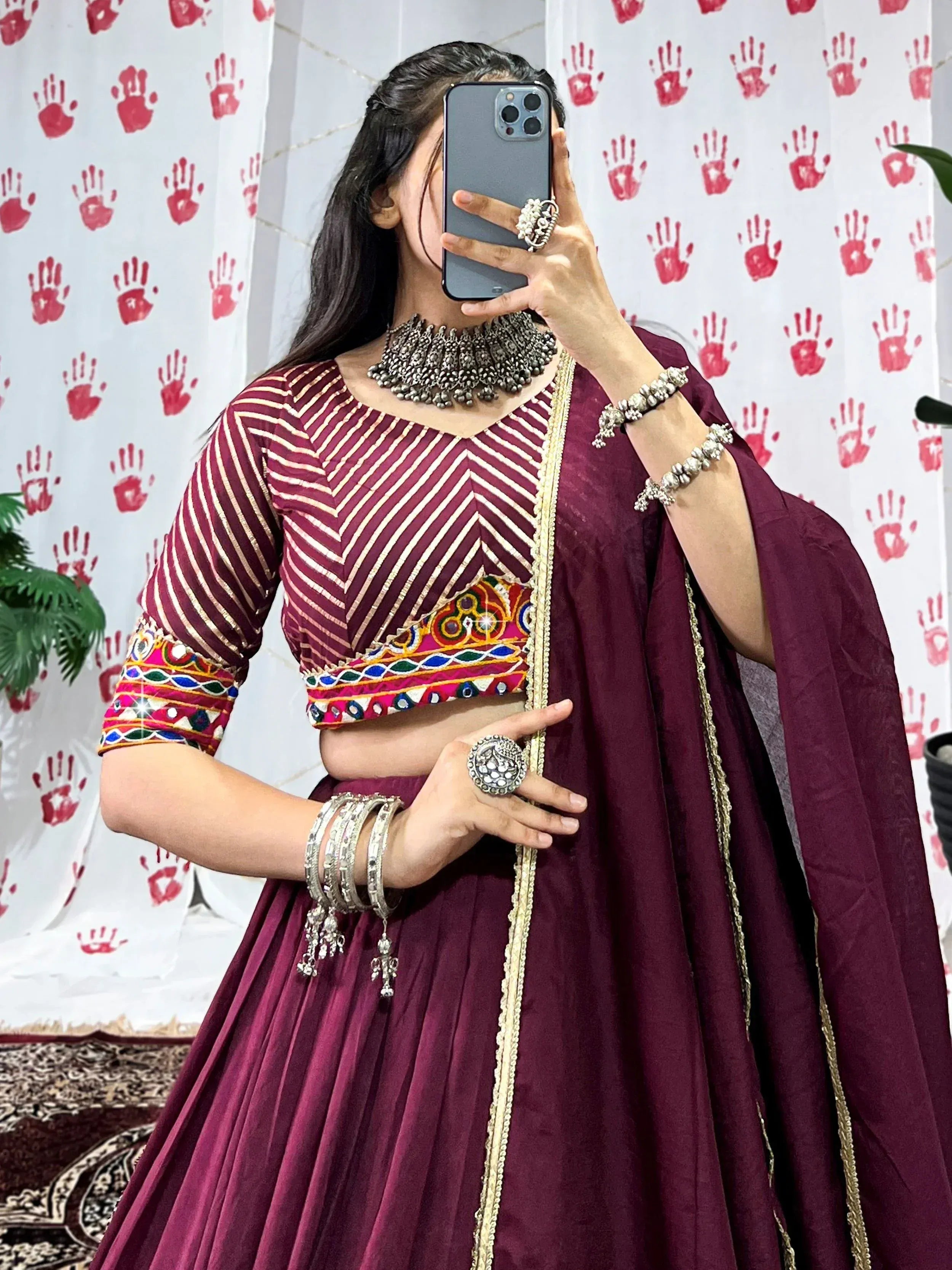 Maroon ethnic lehenga choli with gold stripes, mirror work, and traditional jewelry for Indian wear