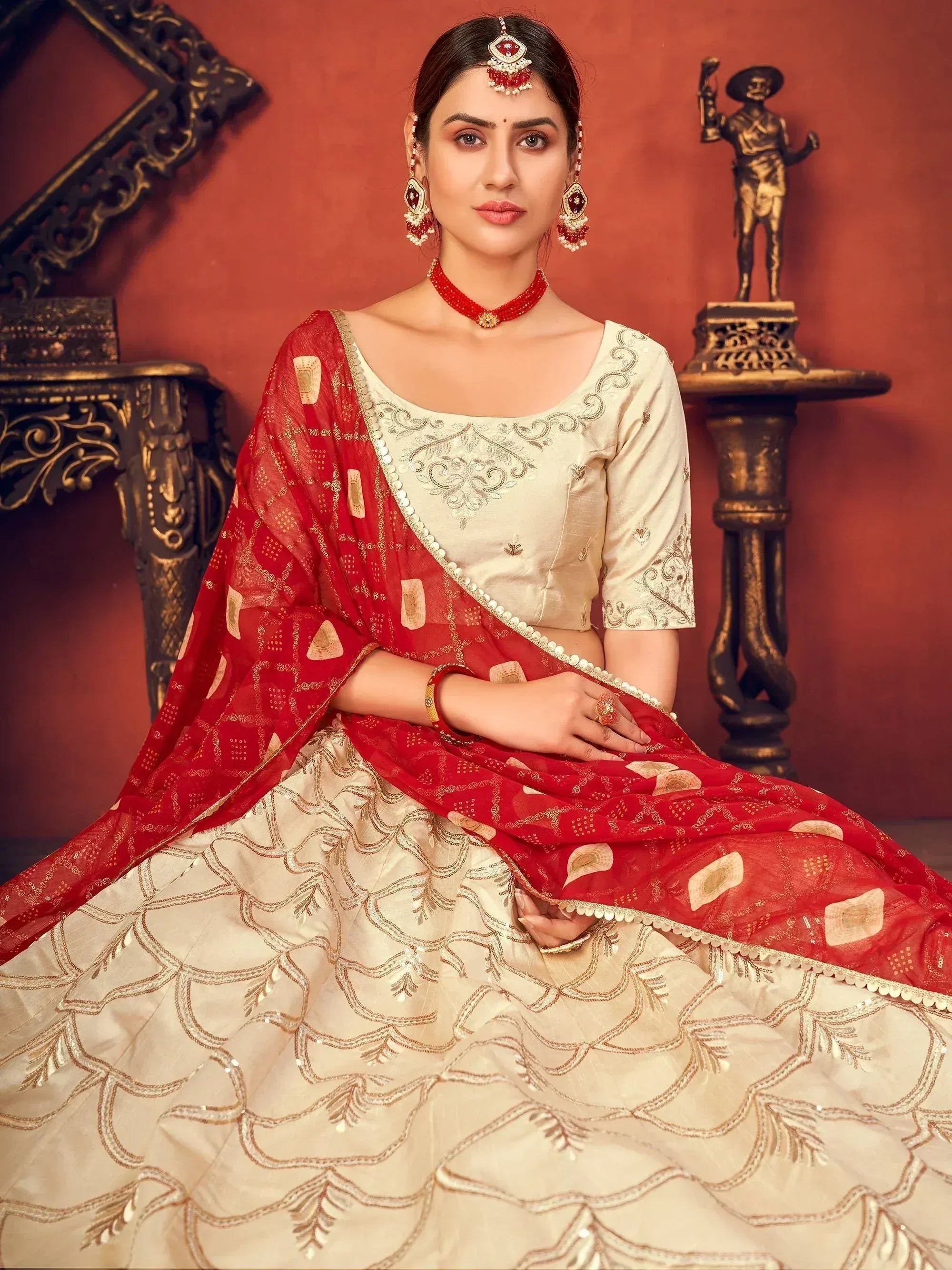 Elegant cream and red designer lehenga choli with intricate gold embroidery and matching dupatta for Indian ethnic wear