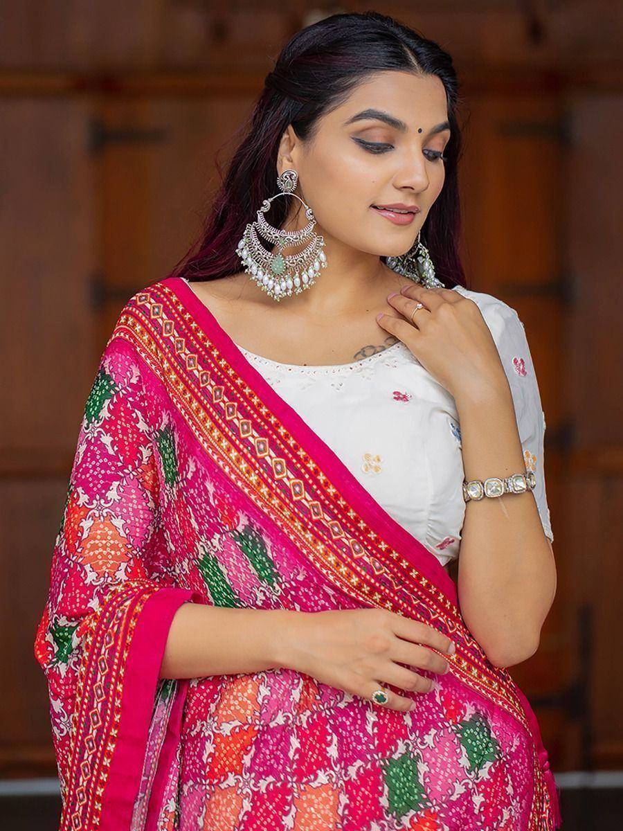 Woman in vibrant pink printed saree with white blouse, traditional jewelry, ethnic Indian wear