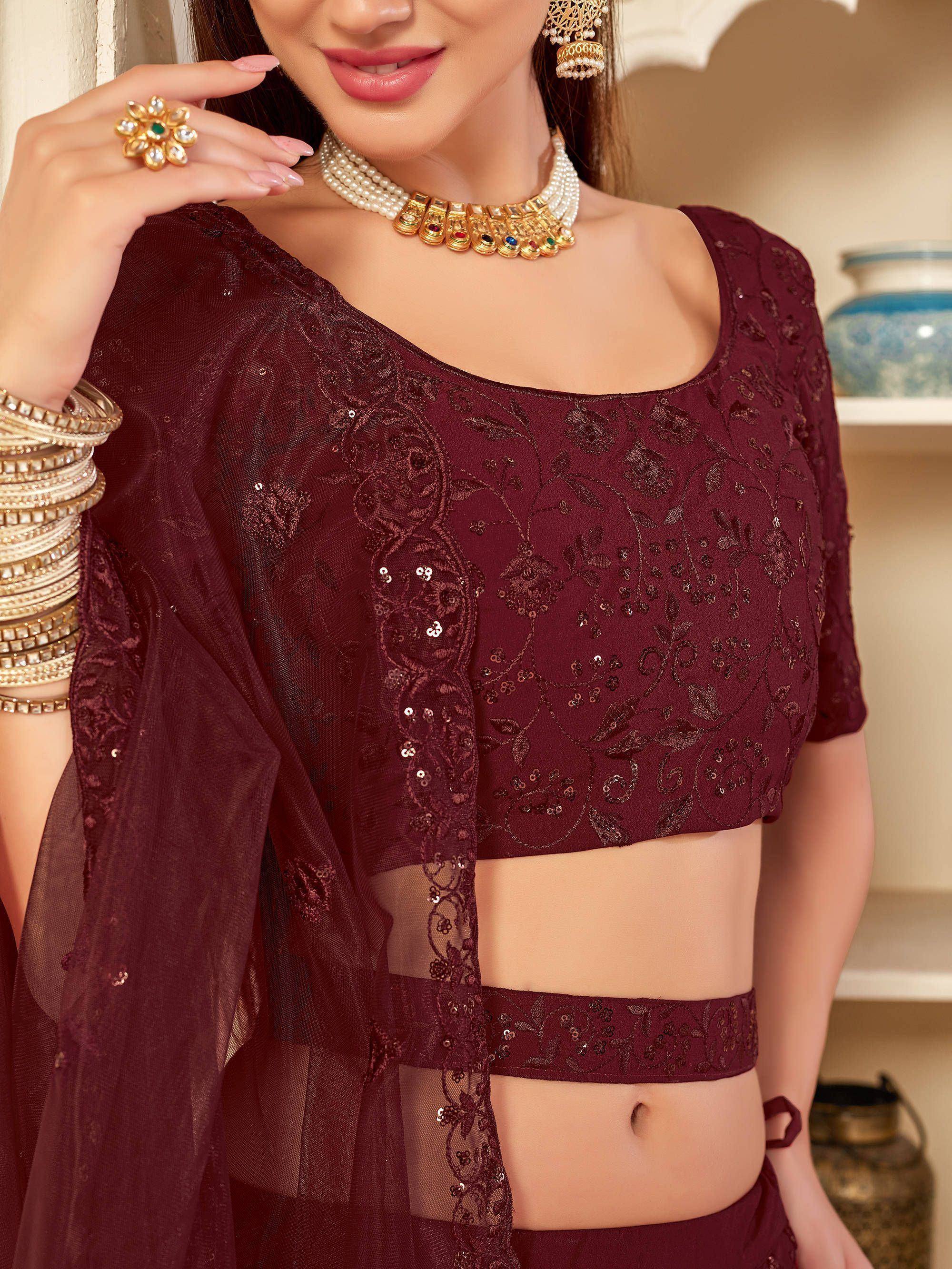Maroon embroidered lehenga choli with sequins, sheer sleeves, and traditional Indian jewelry