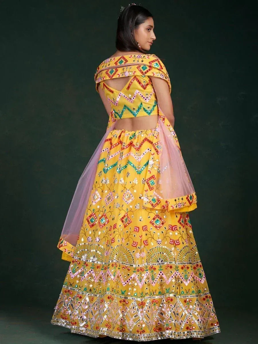Yellow embroidered lehenga choli with mirror work and pink dupatta, ethnic Indian wear
