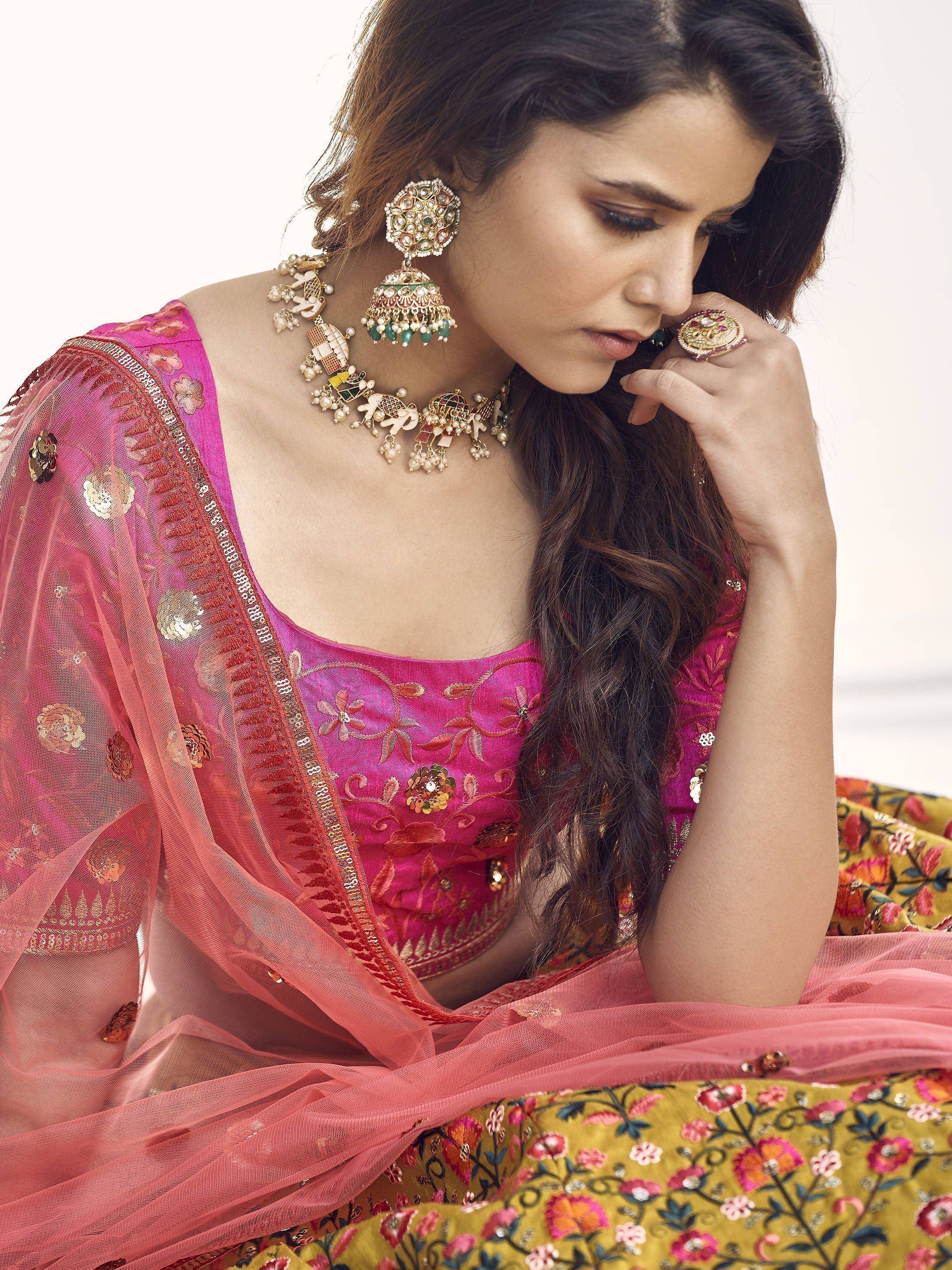 Woman in pink embroidered lehenga choli with gold jewelry, floral dupatta, and traditional Indian attire