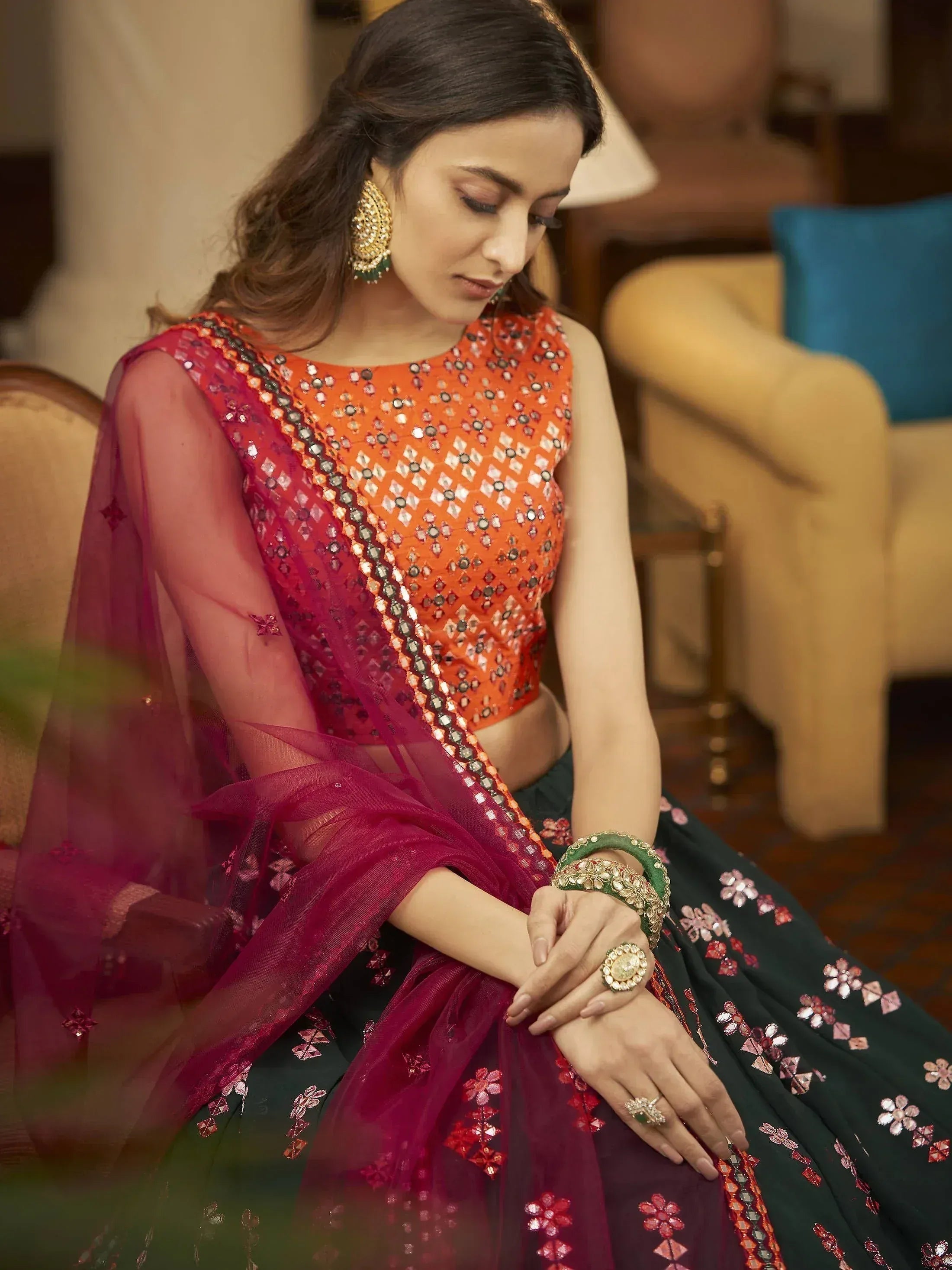 Woman in designer lehenga choli with mirror work, floral embroidery, and sheer dupatta, styled with gold jewelry