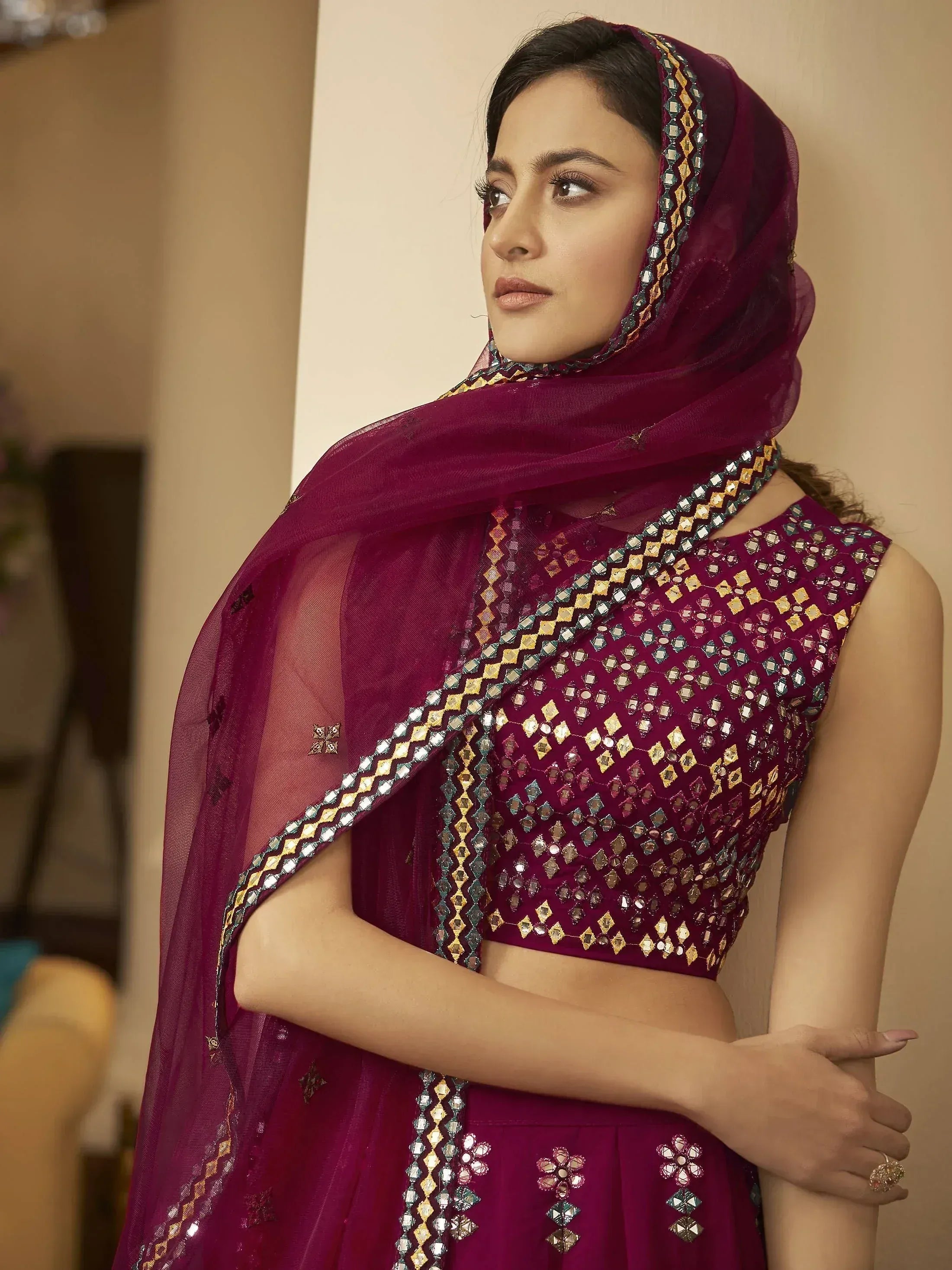 Elegant maroon ethnic lehenga choli with mirror work and sheer dupatta, perfect for Indian weddings and festive occasions.