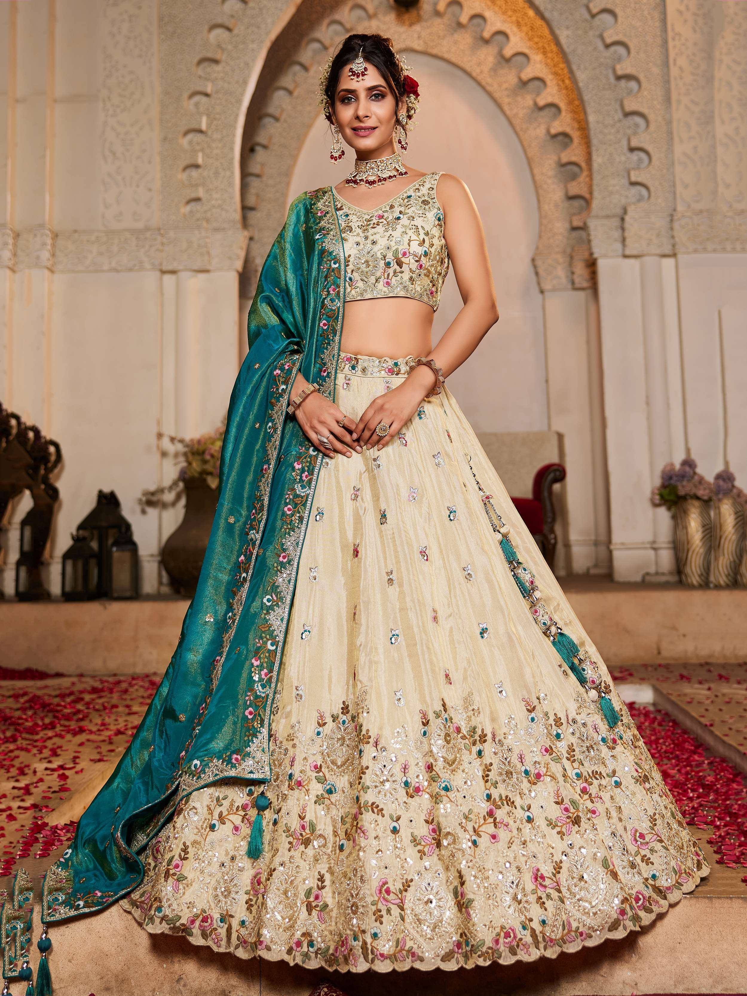 Elegant cream lehenga choli with floral embroidery and teal dupatta, perfect for Indian weddings and festive occasions.