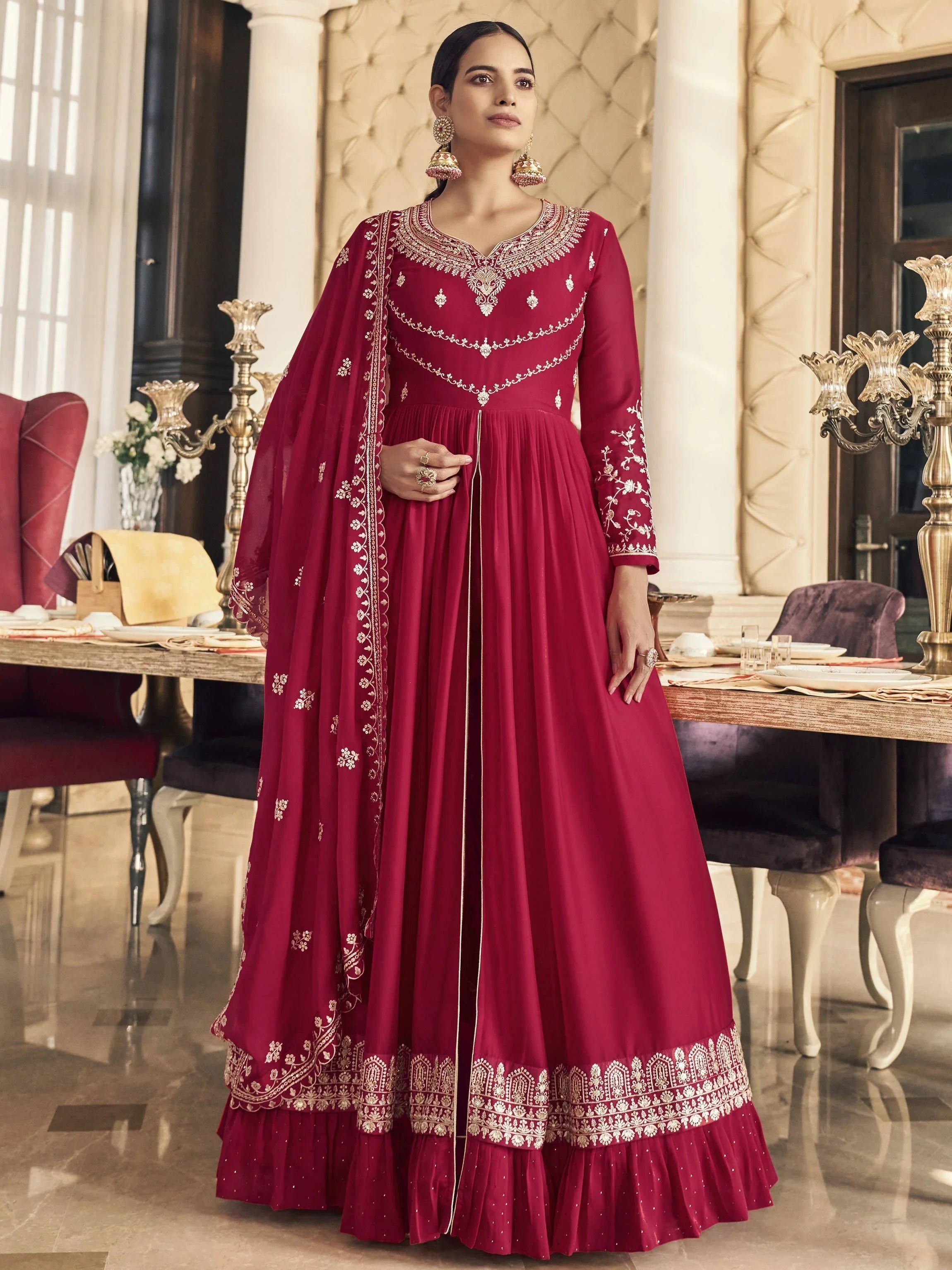 Woman wearing a red embroidered ethnic gown with dupatta in elegant indoor setting