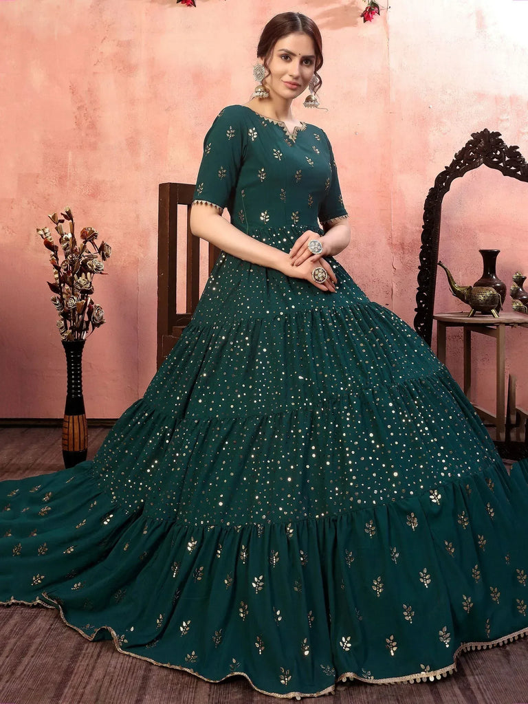 Emerald green ethnic gown with mirror work and tiered skirt, perfect for Indian weddings and festive occasions.