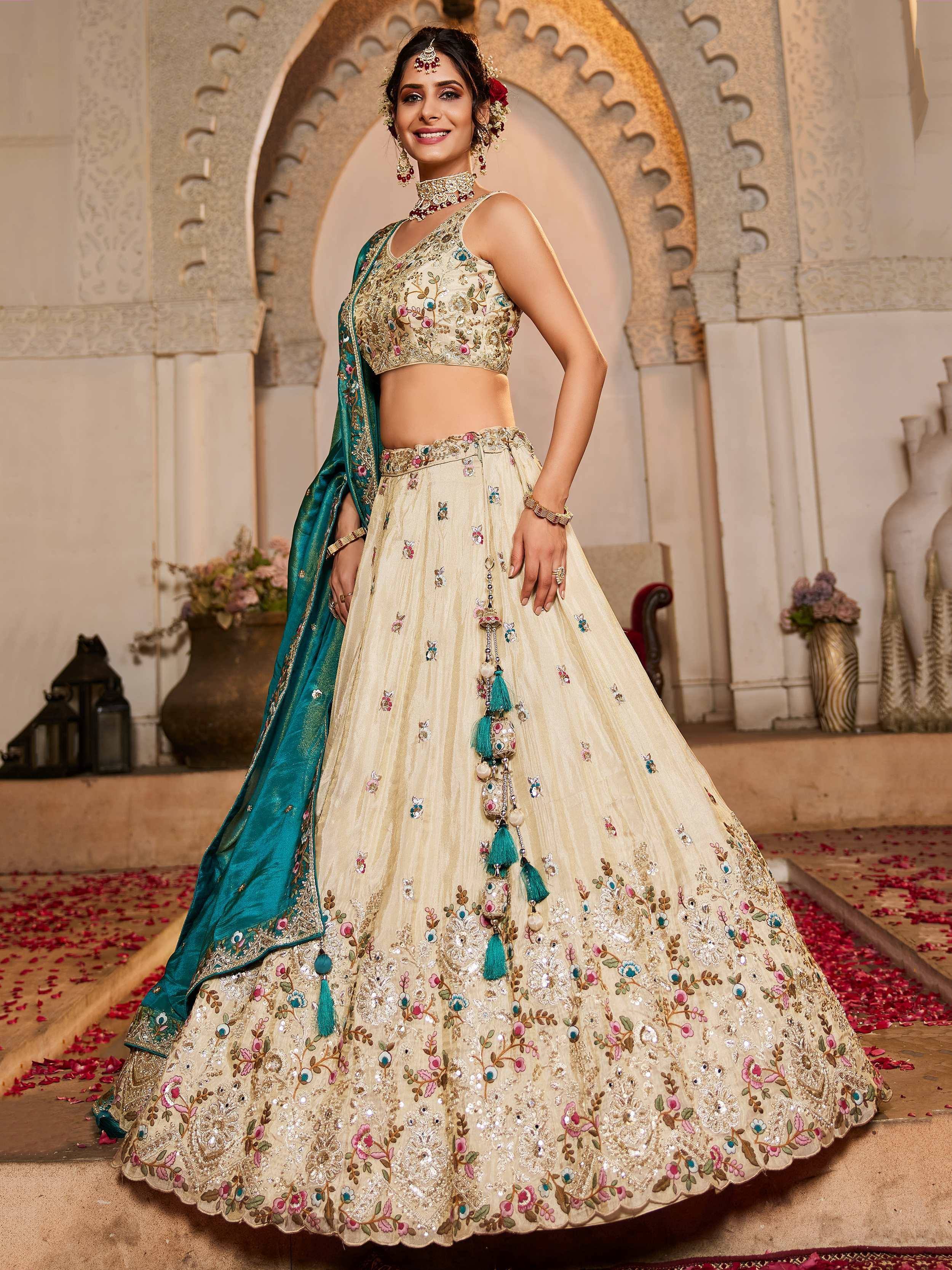 Elegant cream lehenga choli with floral embroidery and teal dupatta, perfect for Indian weddings and festive occasions.
