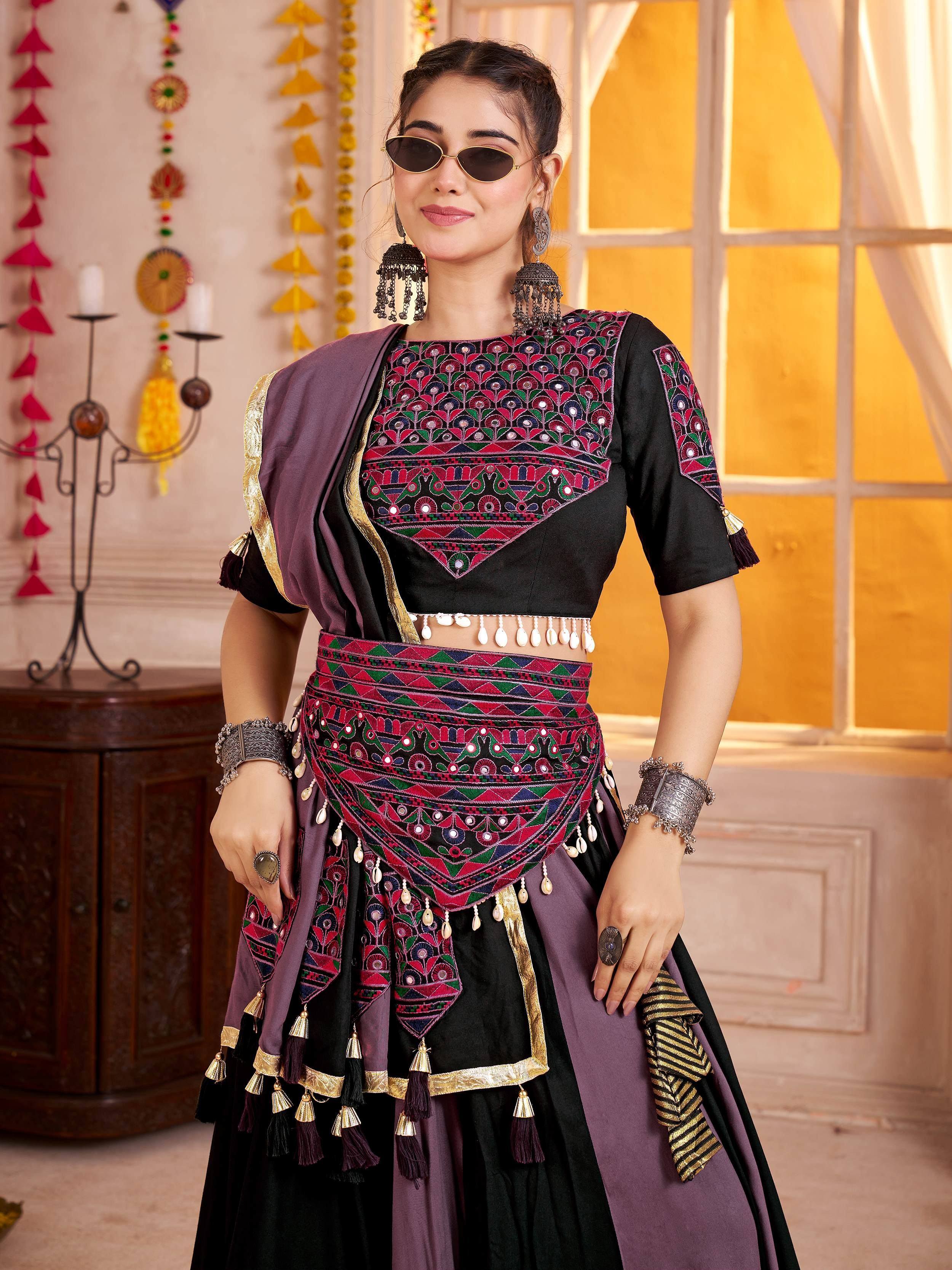 Black and purple ethnic lehenga choli with mirror work, tassels, and traditional jewelry for festive occasions