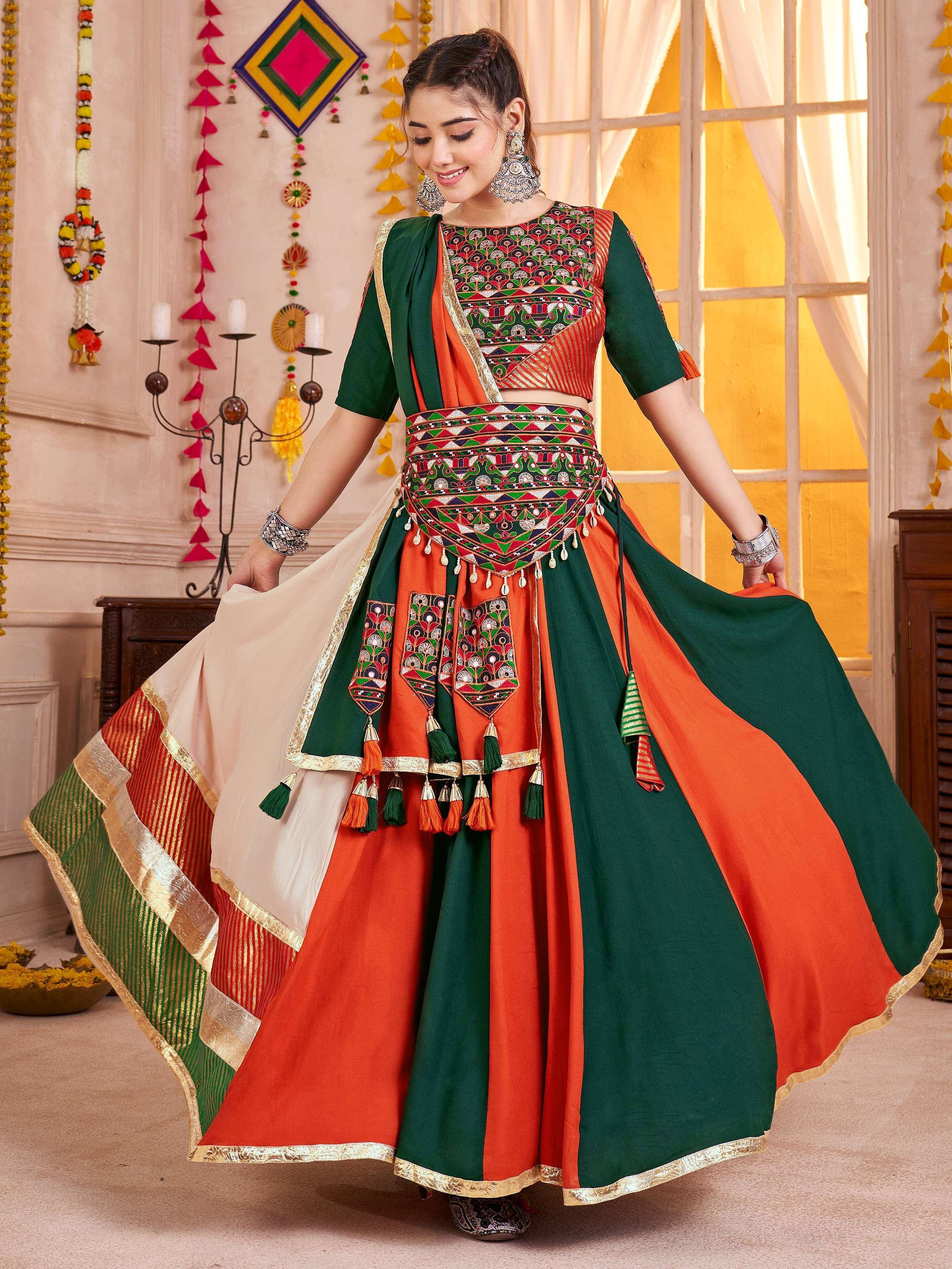 Woman in vibrant green and orange embroidered lehenga choli with tassels, perfect for festive Indian occasions.
