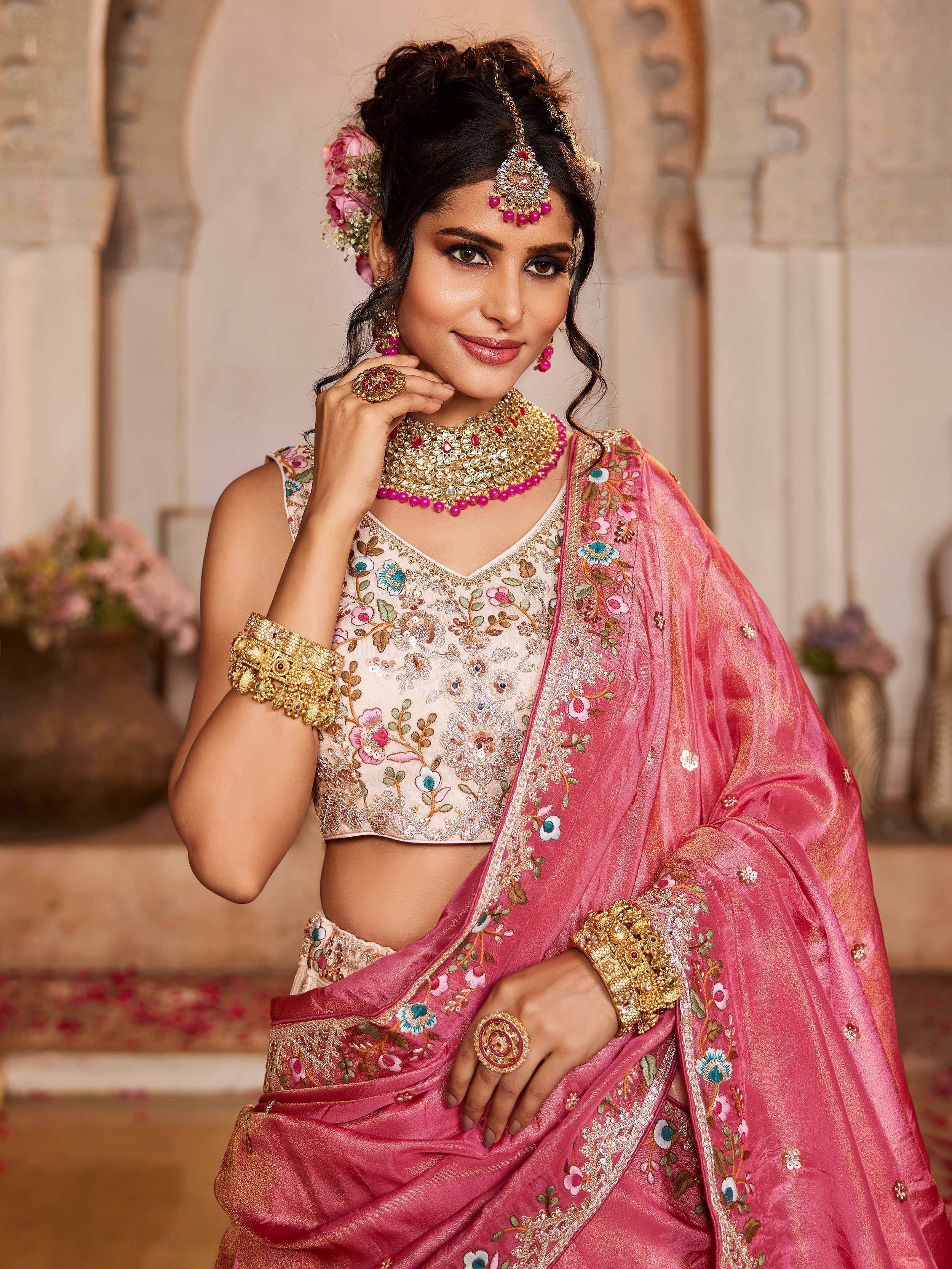 Elegant pink embroidered lehenga choli with floral motifs, gold jewelry, and traditional Indian bridal styling