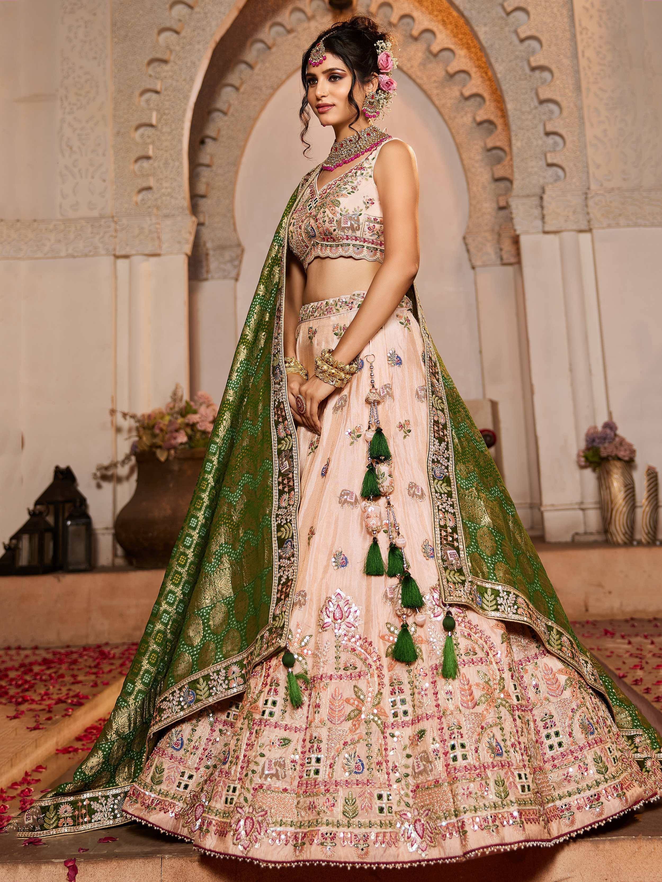 Elegant peach lehenga choli with green dupatta, intricate floral embroidery, and tassels for Indian weddings.