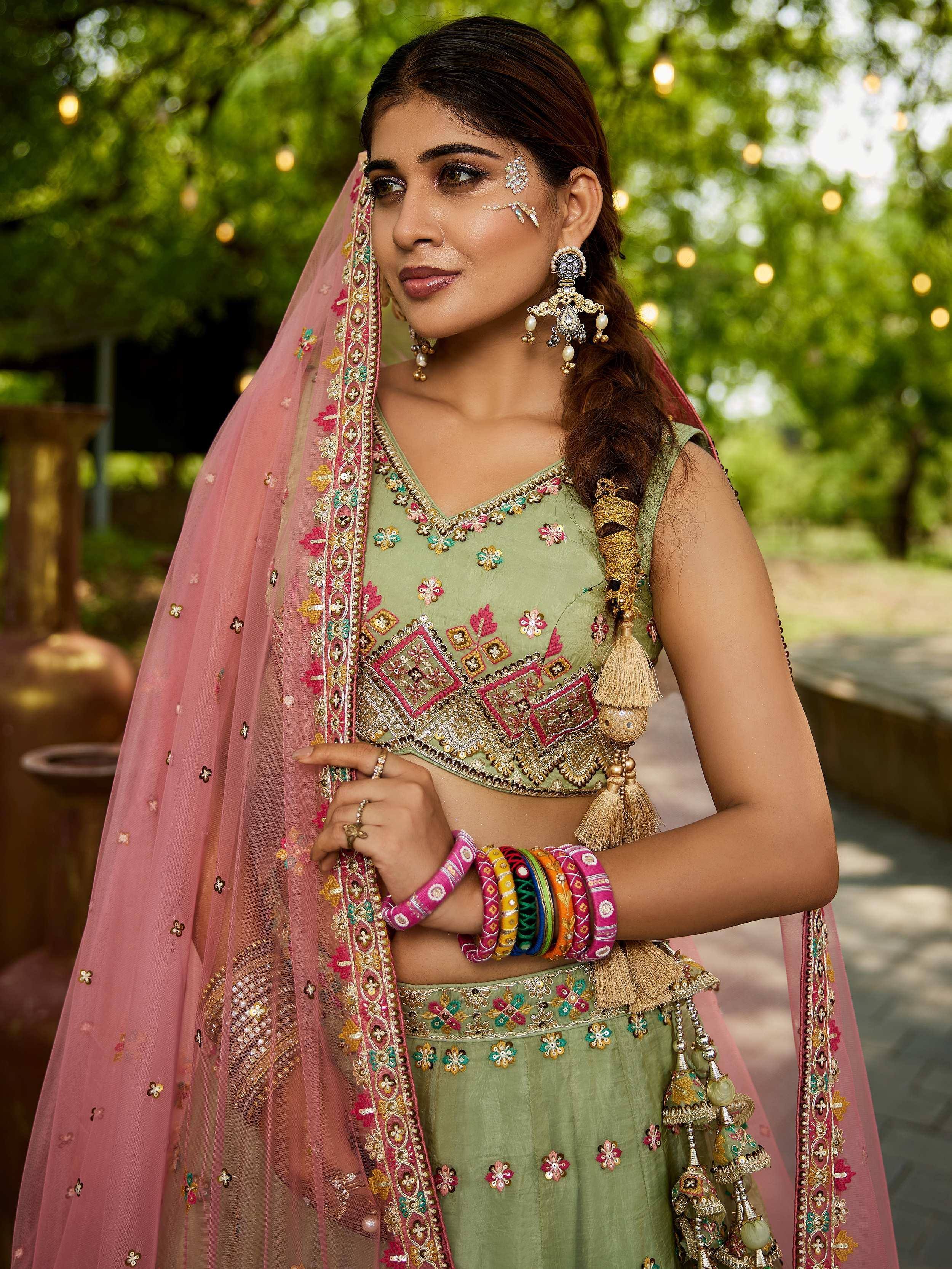Woman in green embroidered lehenga choli with pink dupatta, traditional Indian ethnic wear for weddings and festivals