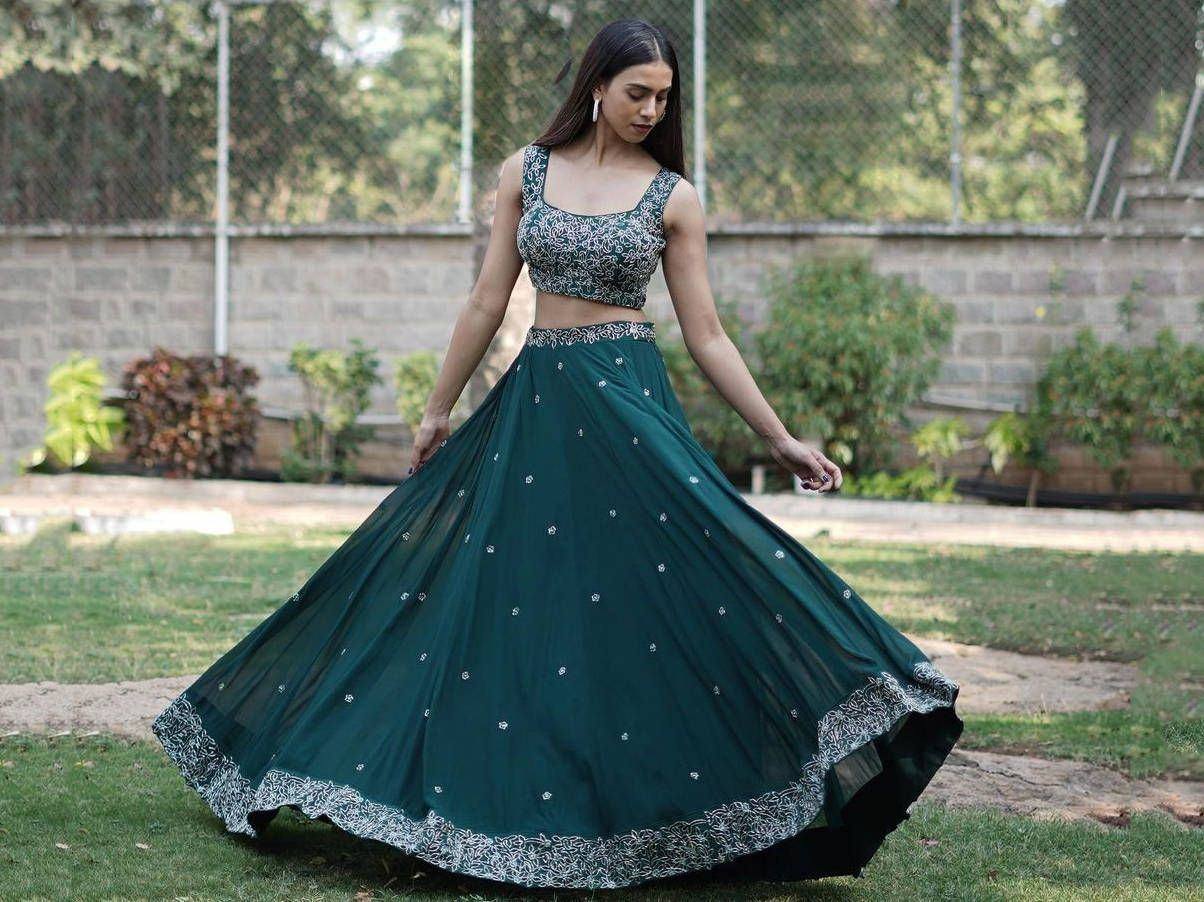 Woman twirling in emerald green lehenga choli with silver embroidery, perfect for Indian ethnic wear occasions