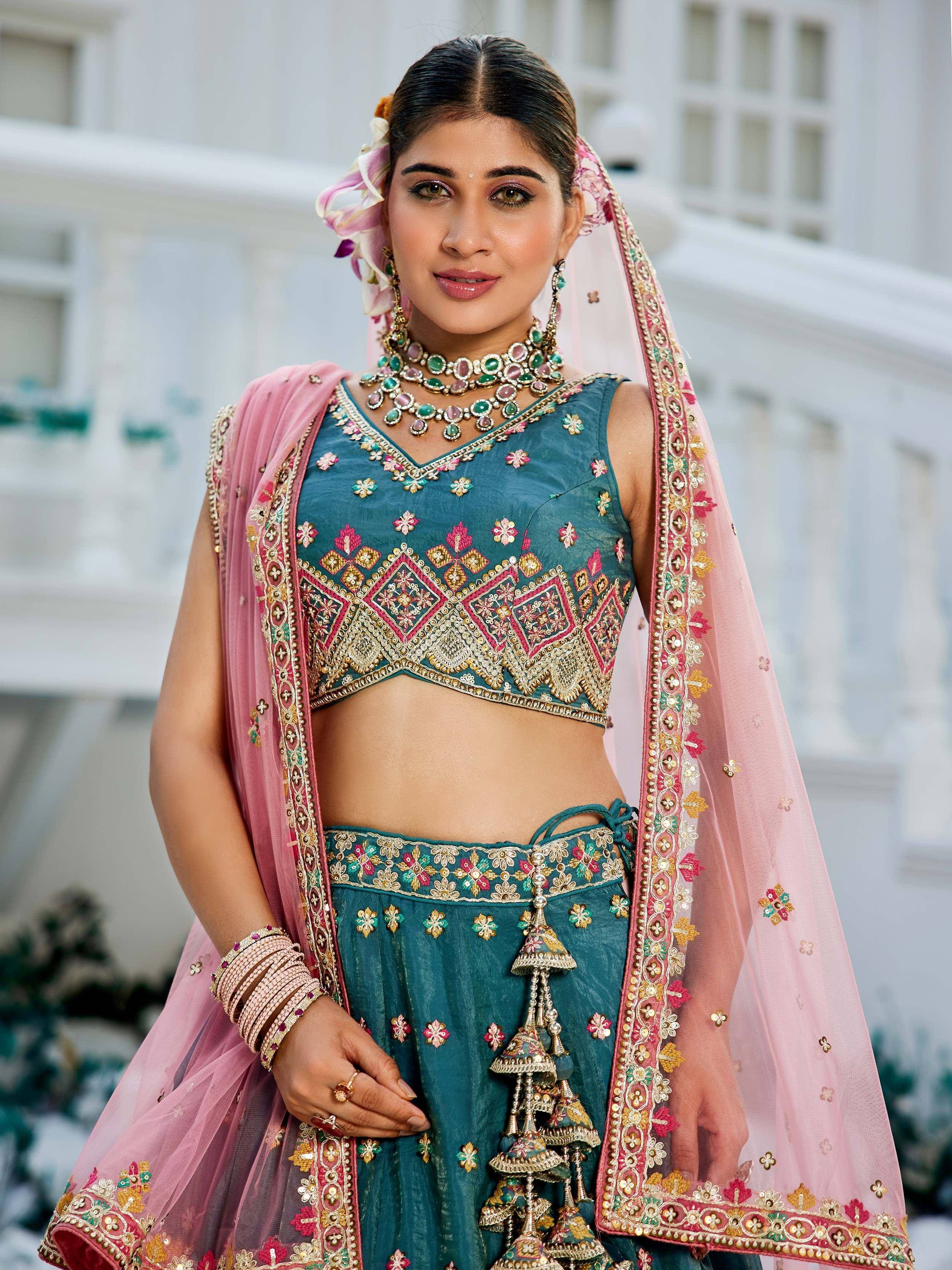 Teal embroidered lehenga choli with pink dupatta, floral jewelry, and traditional Indian ethnic wear