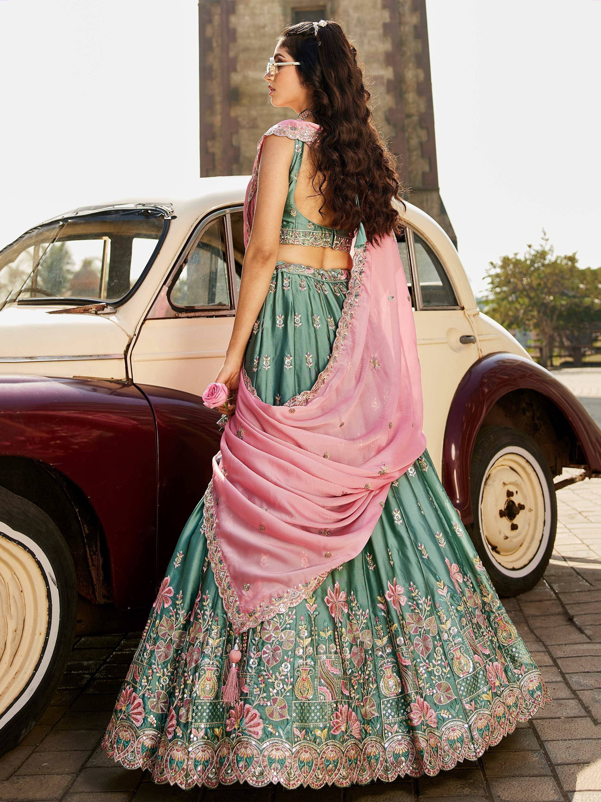Green embroidered lehenga choli with pink dupatta, styled with vintage car backdrop