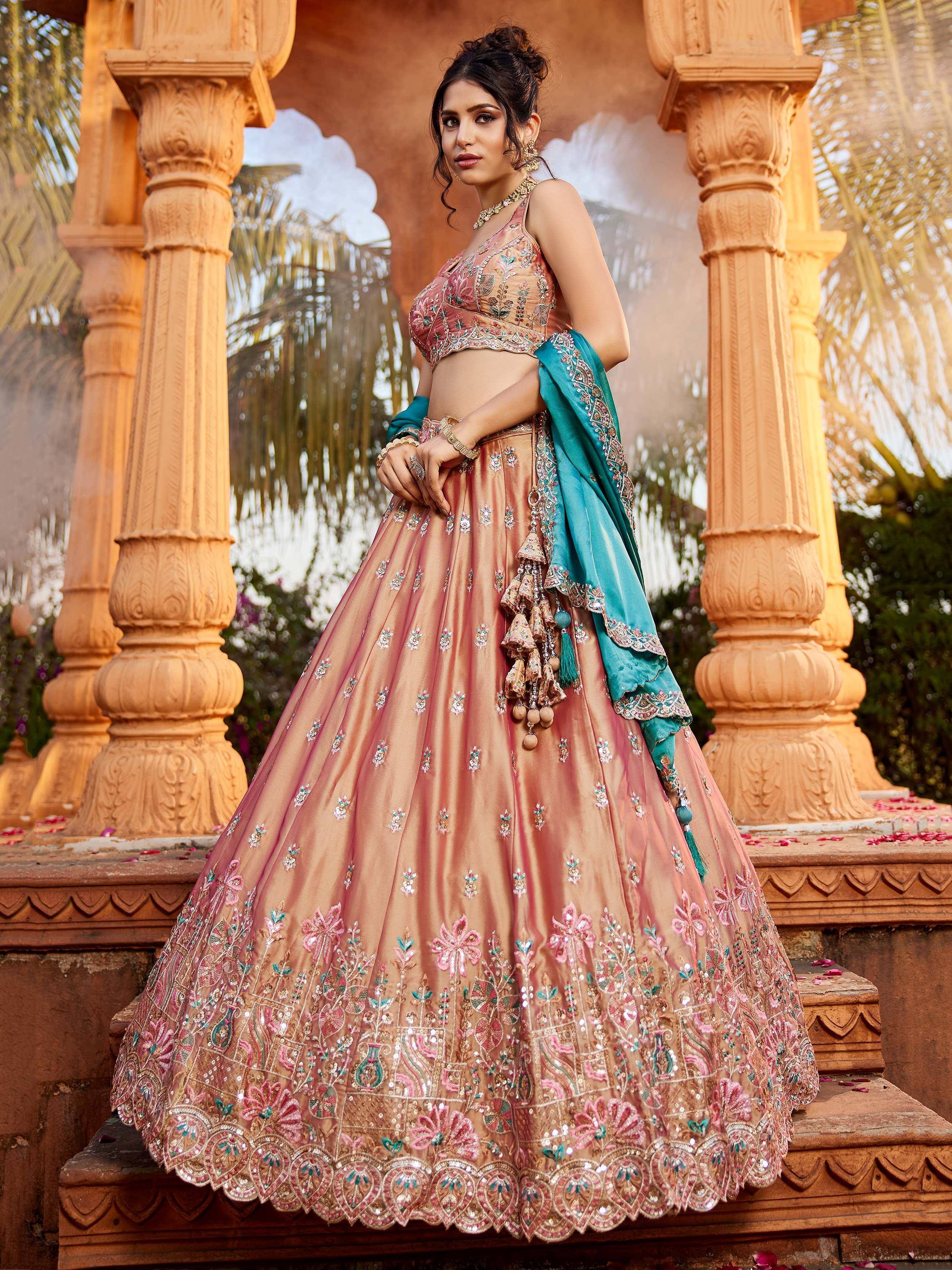 Elegant peach lehenga choli with floral embroidery and teal dupatta, perfect for Indian weddings and festive occasions.