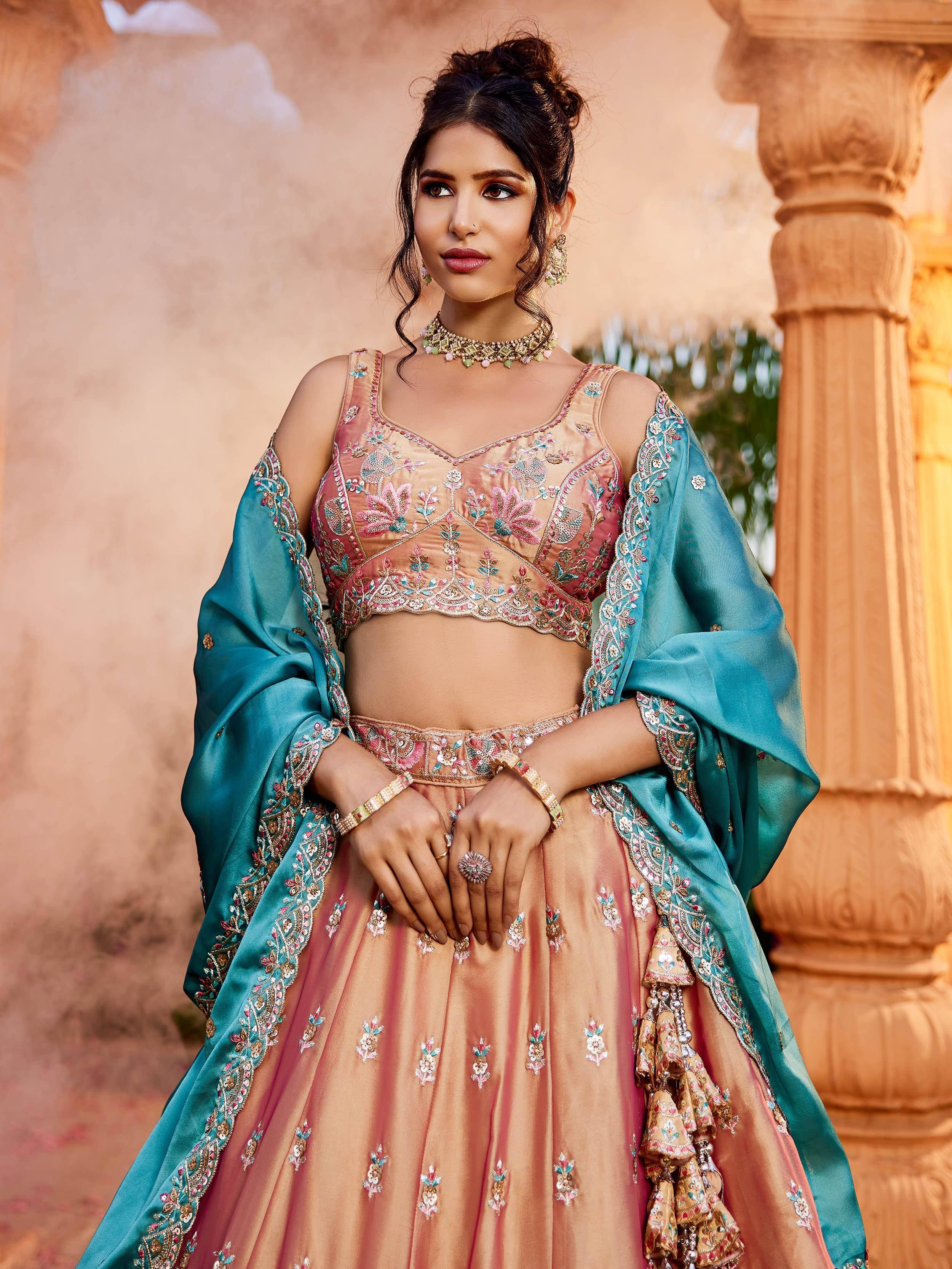 Elegant peach lehenga choli with teal dupatta, floral embroidery, perfect for Indian weddings and festive occasions