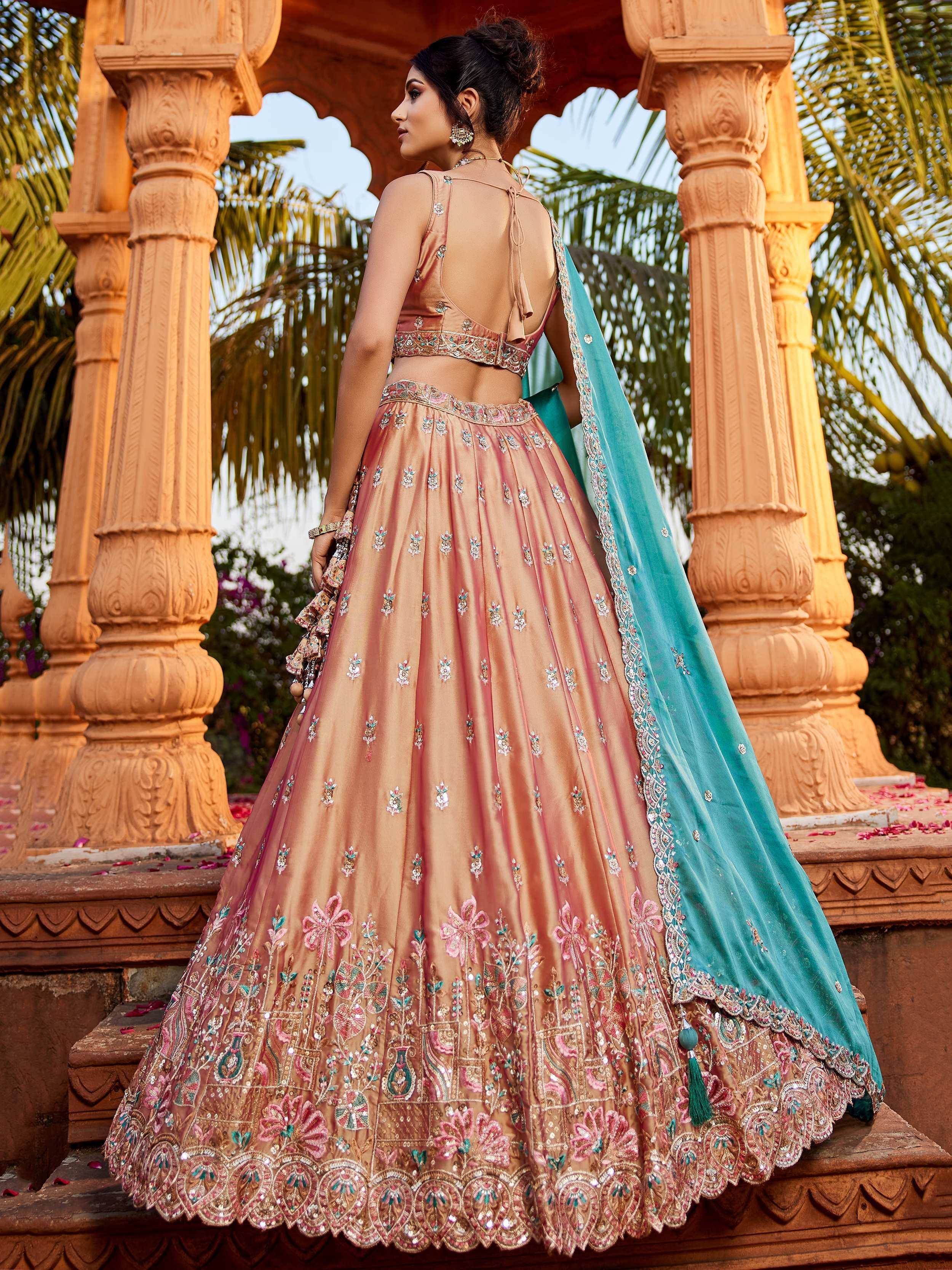 Elegant peach lehenga choli with floral embroidery and teal dupatta, perfect for Indian weddings and festive occasions.