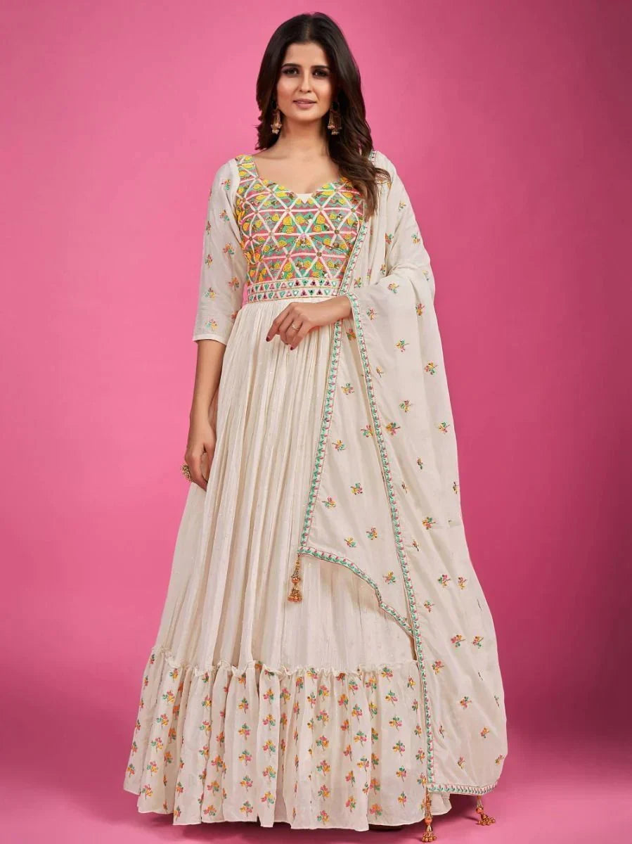 Woman in cream embroidered ethnic gown with multicolor bodice and dupatta, pink background