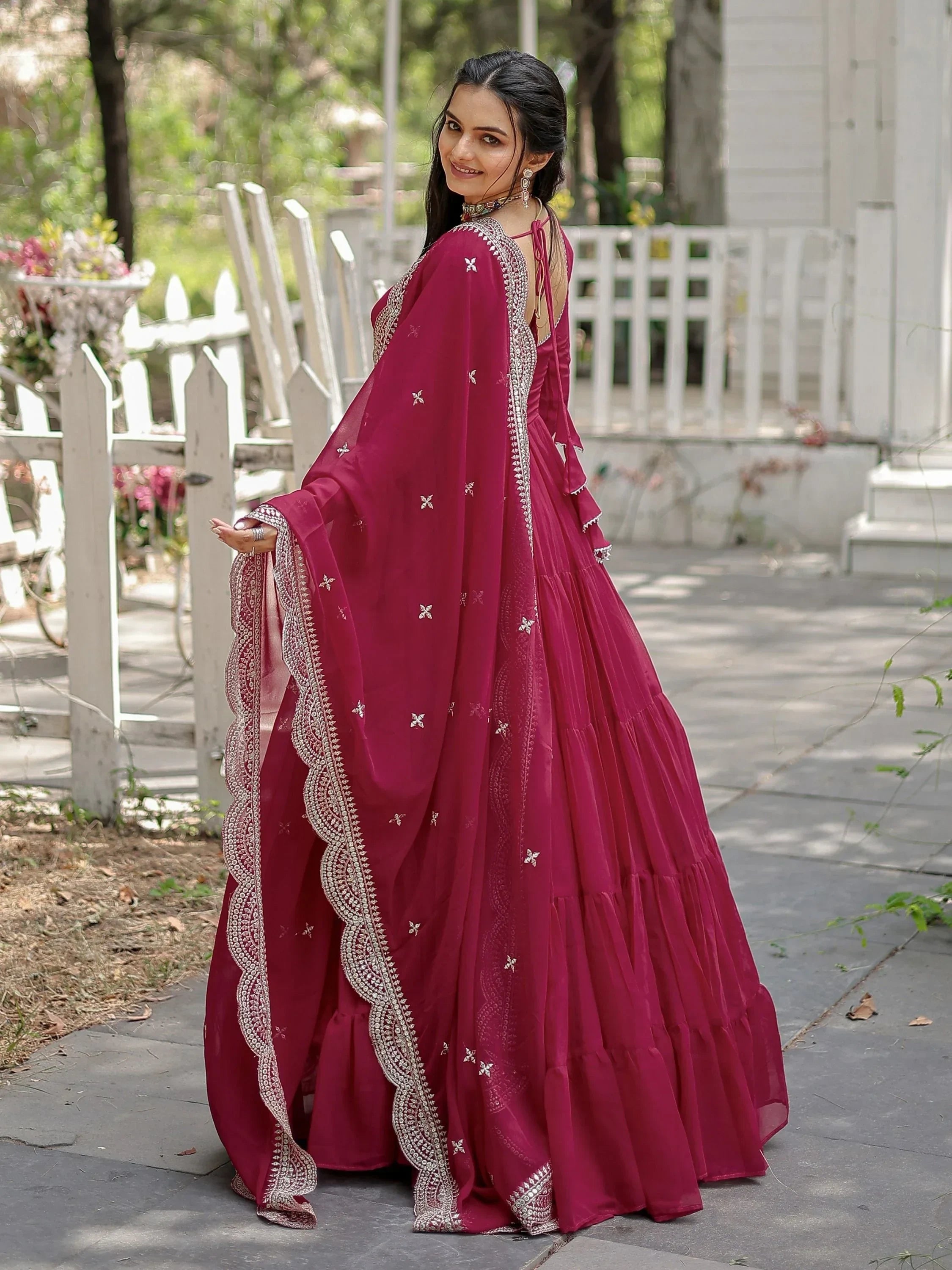 Woman wearing a pink embroidered lehenga choli with dupatta, outdoor garden setting