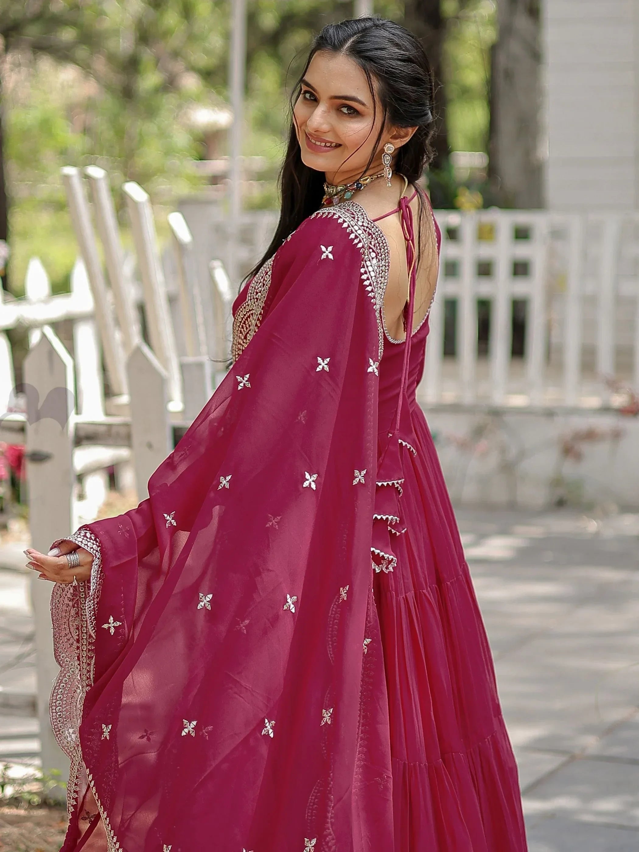 Woman in magenta embroidered lehenga choli with dupatta, outdoor setting
