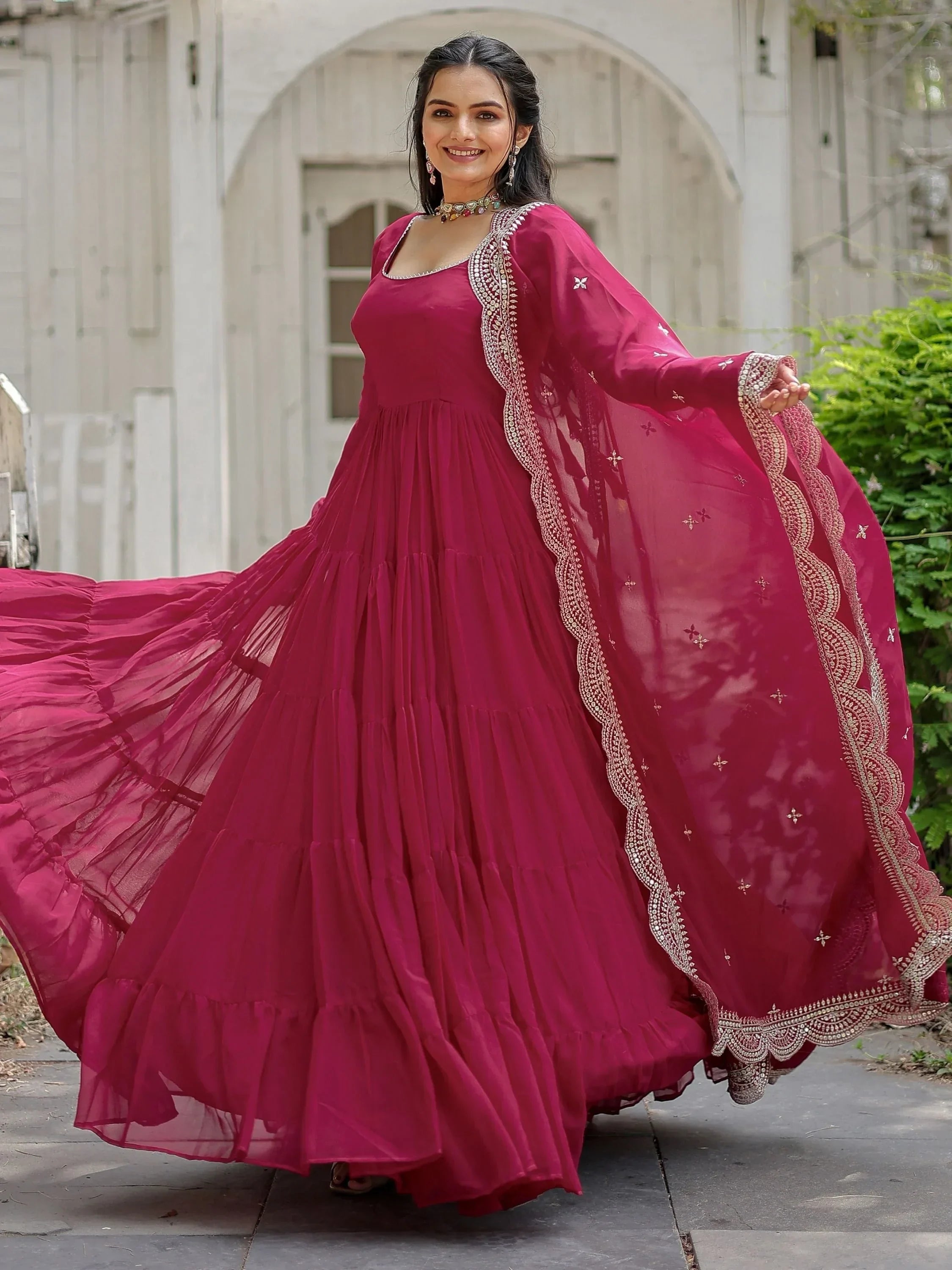 Woman wearing a pink embroidered ethnic gown with matching dupatta outdoors