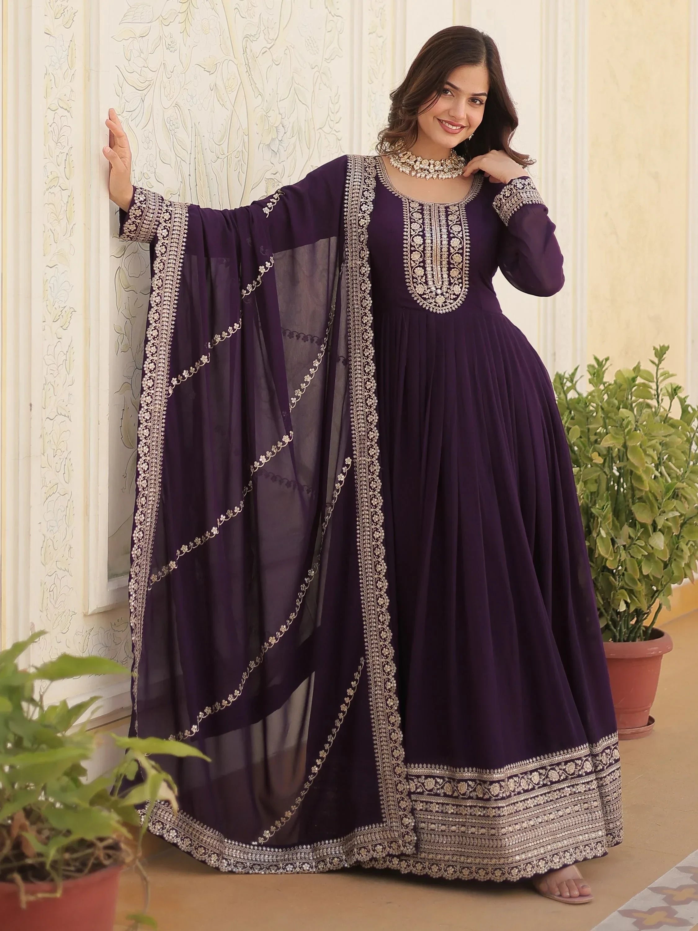Woman wearing wine purple embroidered ethnic gown with dupatta indoors