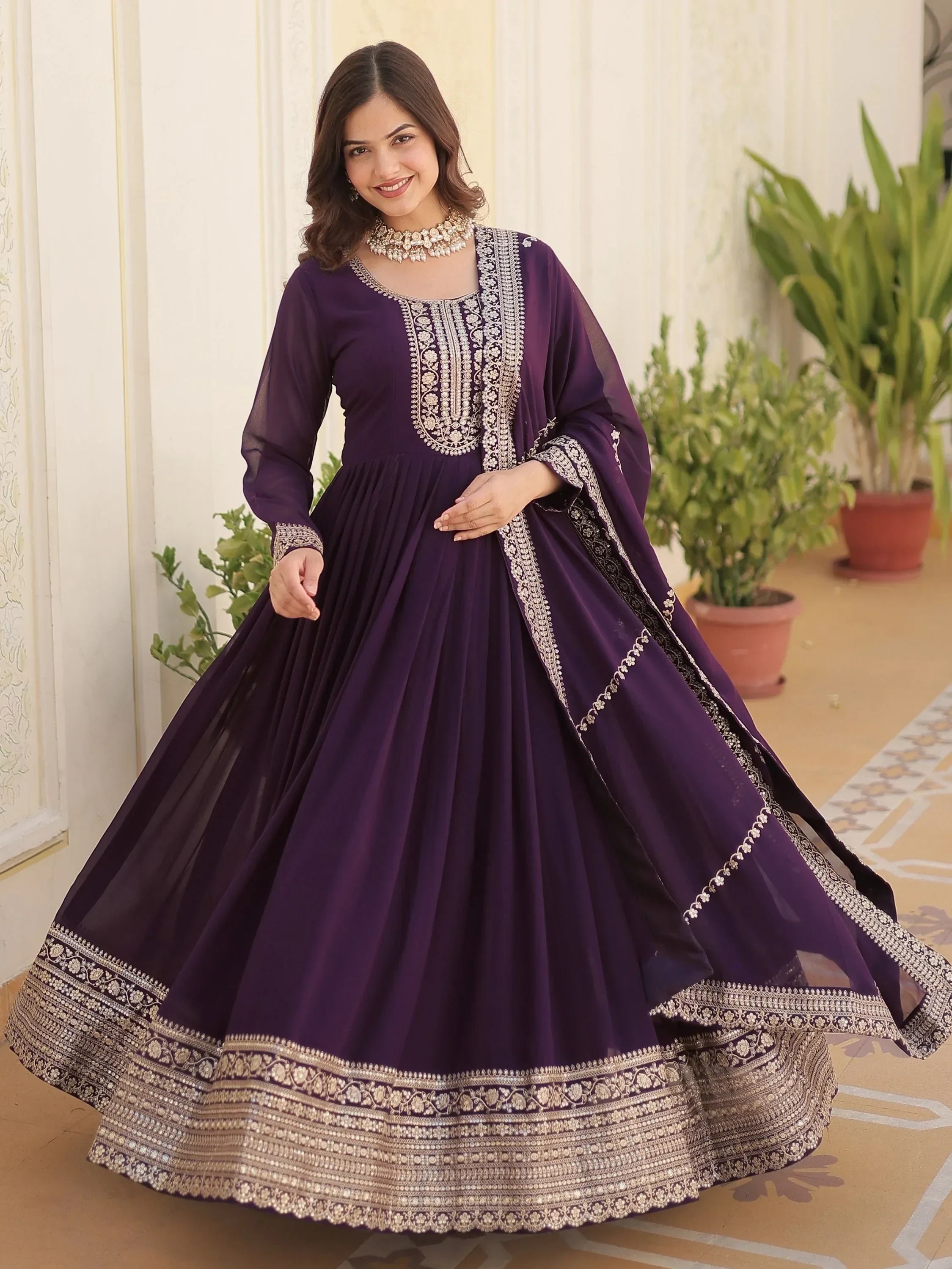 Woman wearing a wine purple embroidered Indian ethnic gown with dupatta, indoor setting