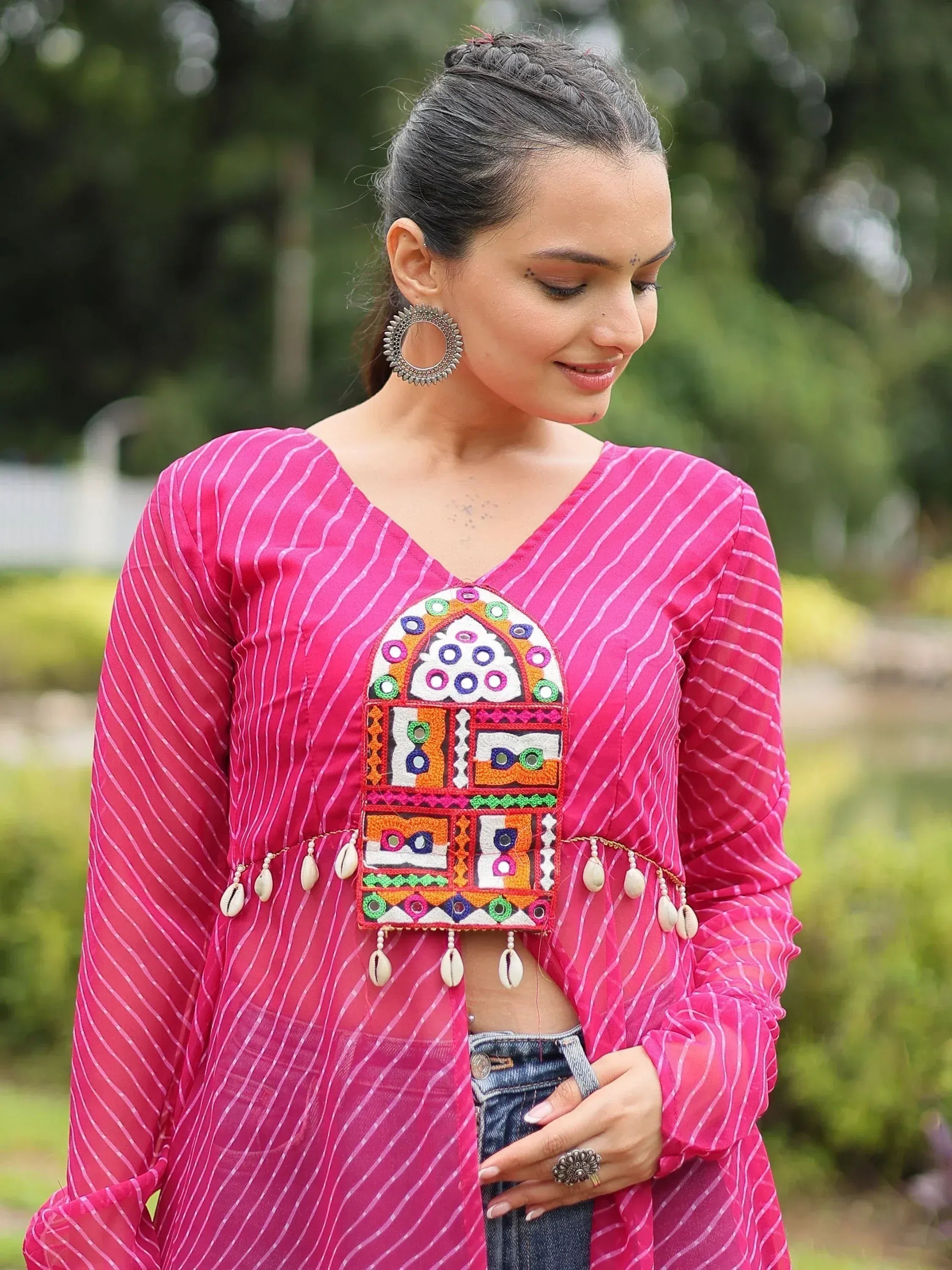 Pink striped ethnic kurti with colorful embroidery and shell tassels, paired with jeans