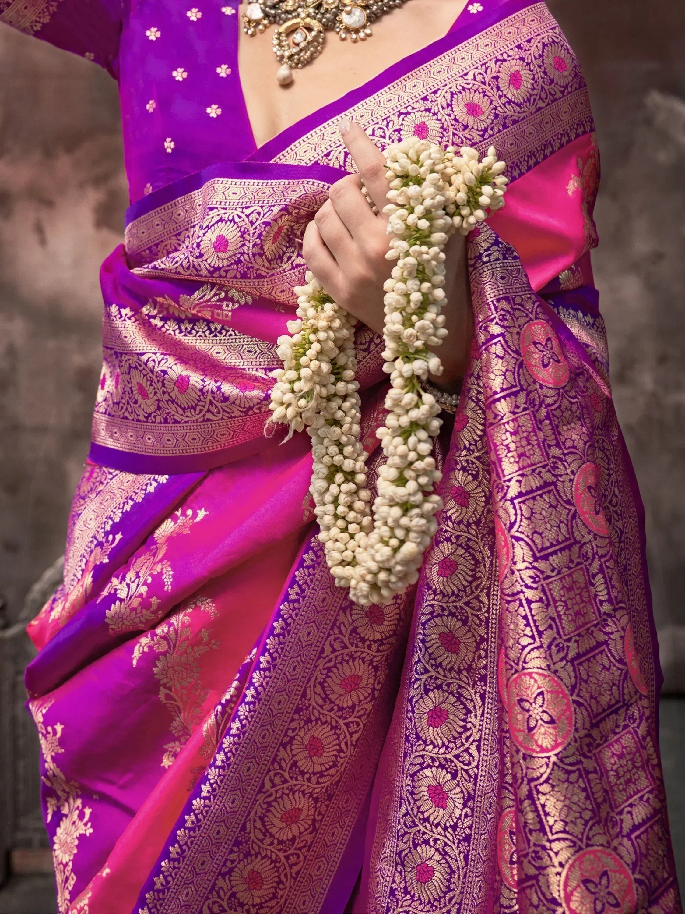 Purple and pink designer saree with gold embroidery, floral motifs, and jasmine garland for Indian ethnic wear